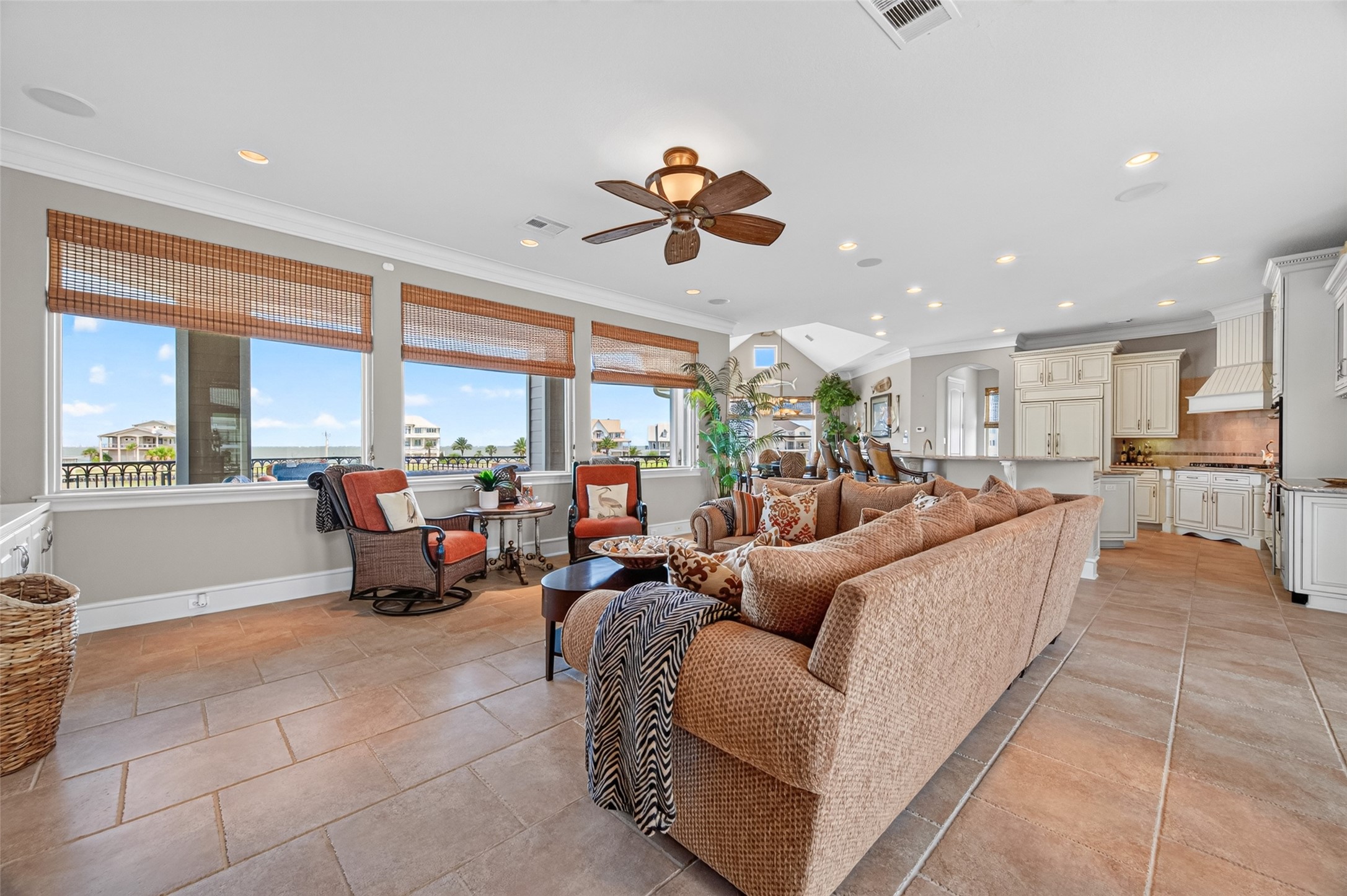 Spacious open-concept living area with abundant natural light, featuring a cozy seating arrangement, tile flooring, and a modern kitchen equipped with elegant cabinetry.