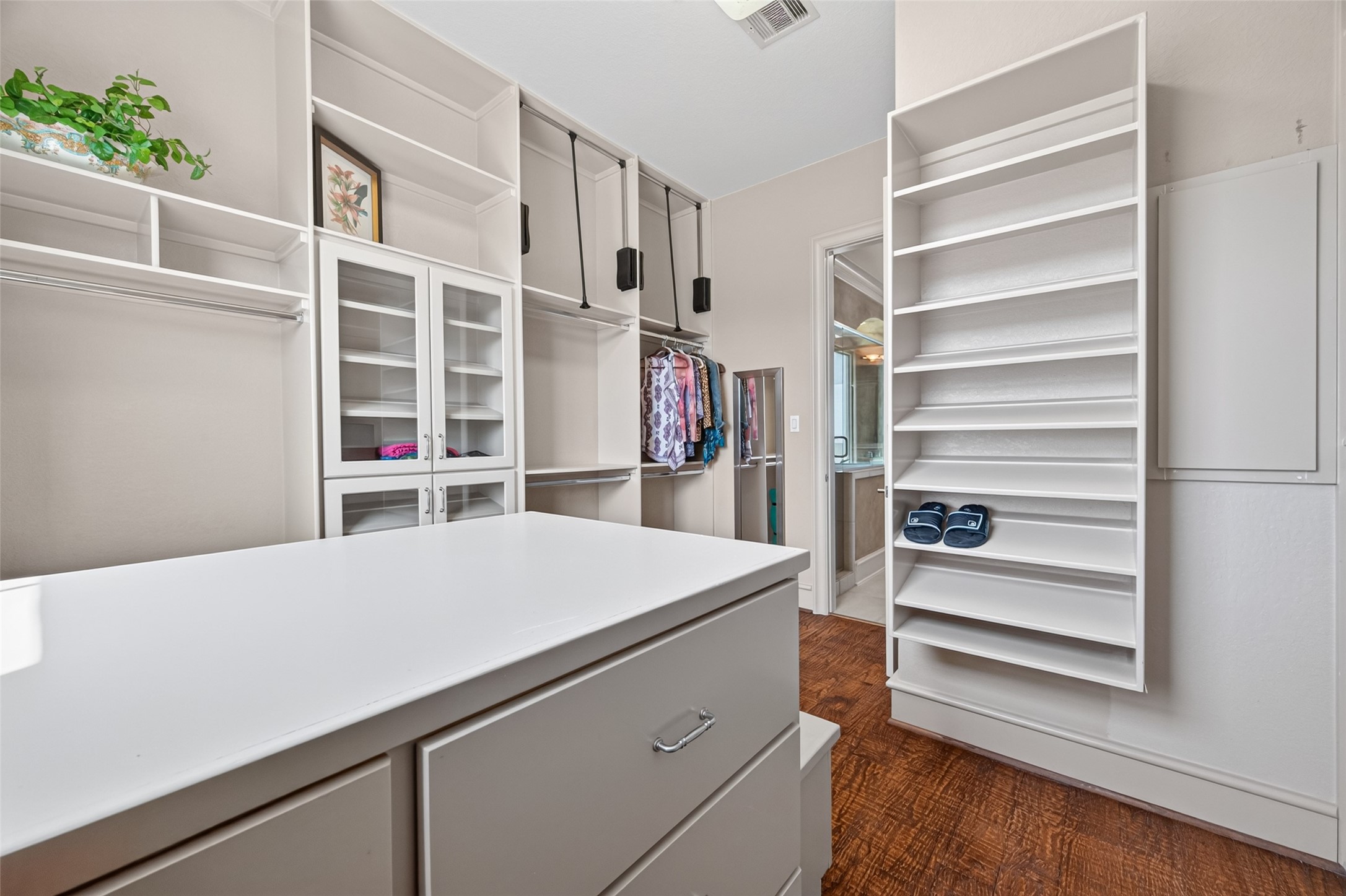 Spacious walk-in closet with ample shelving, hanging space, and a central island for organization, featuring elegant wood flooring.