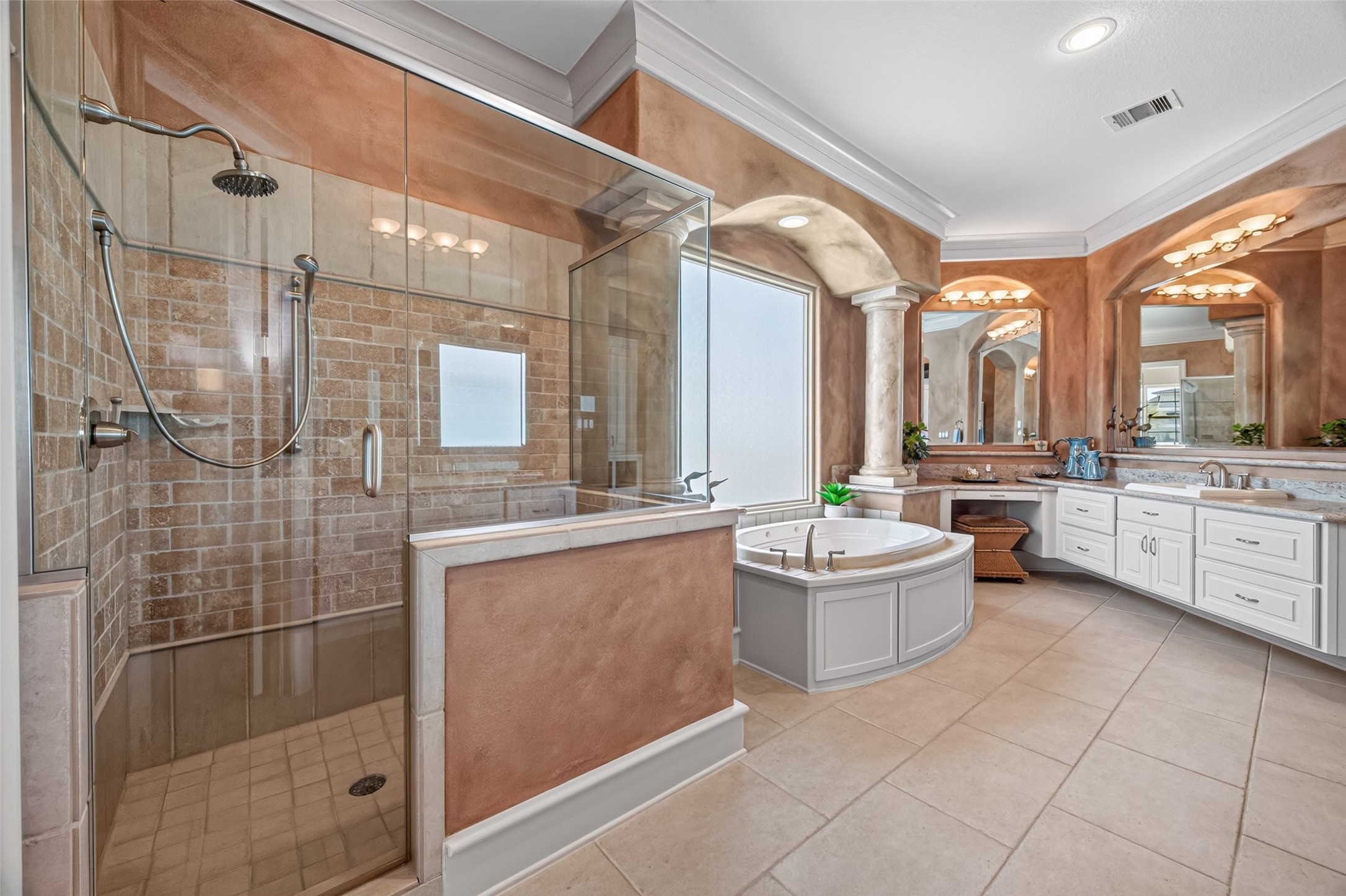Luxurious bathroom featuring a spacious glass-enclosed shower, elegant soaking tub, and dual vanities with ample counter space, all accented by warm tones and stylish finishes.