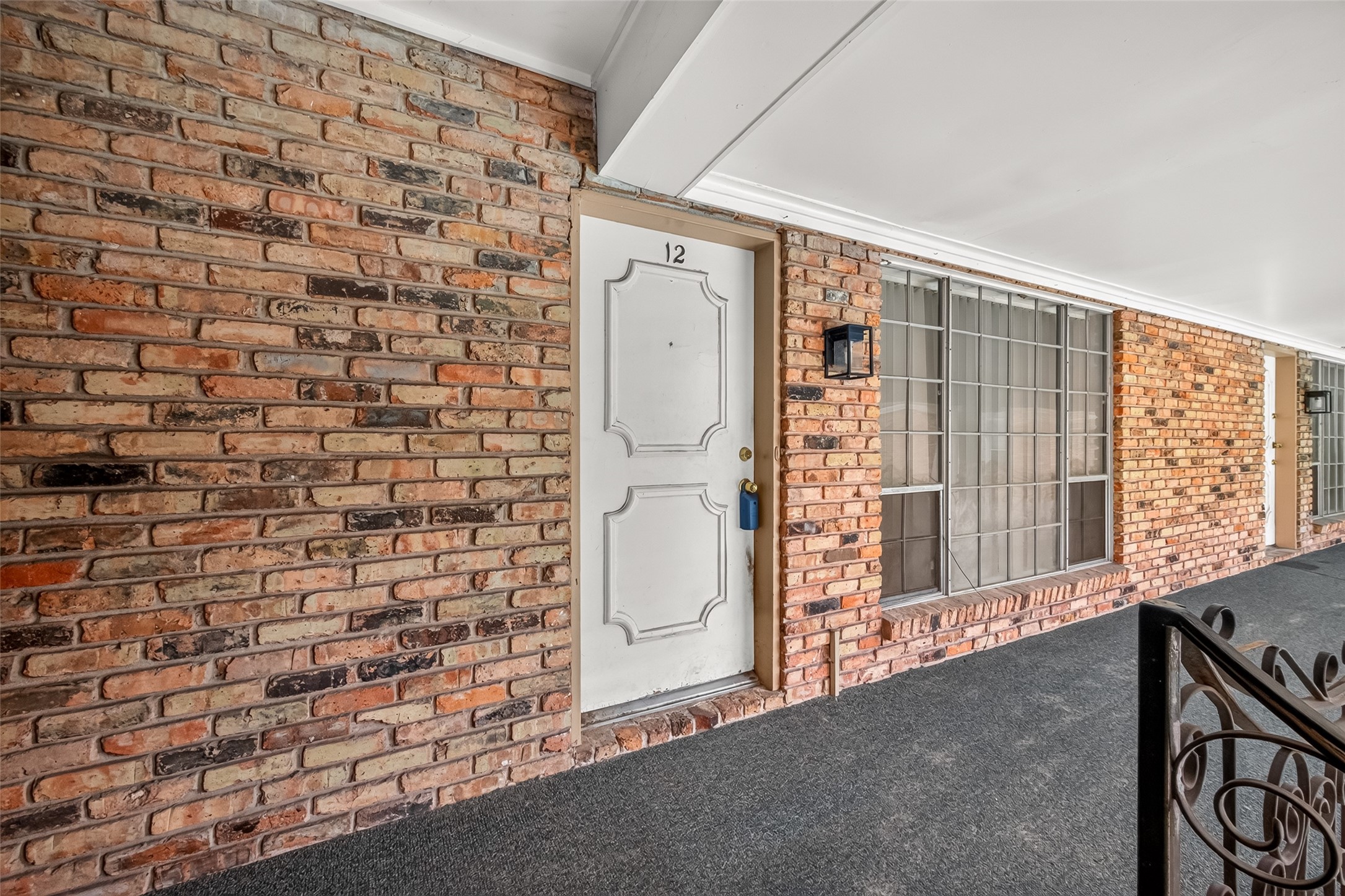 Charming brick exterior with a classic white door and large windows, offering a welcoming entrance.