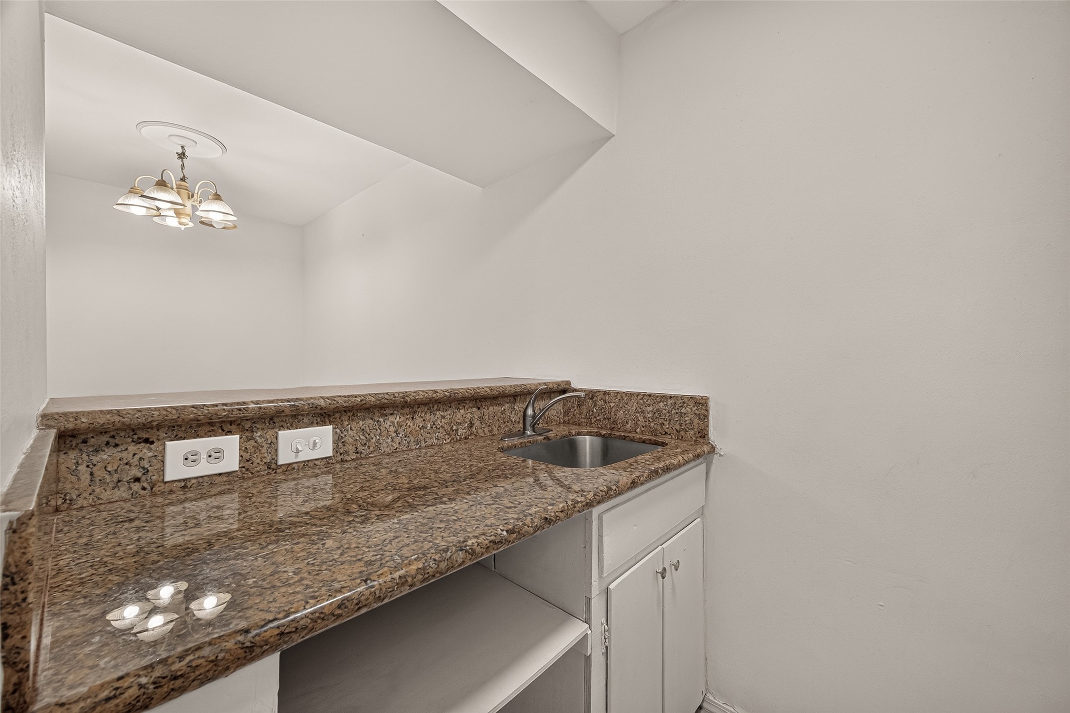 Cozy kitchenette with sleek granite countertops, a compact sink, and ample cabinet storage, perfect for small gatherings.