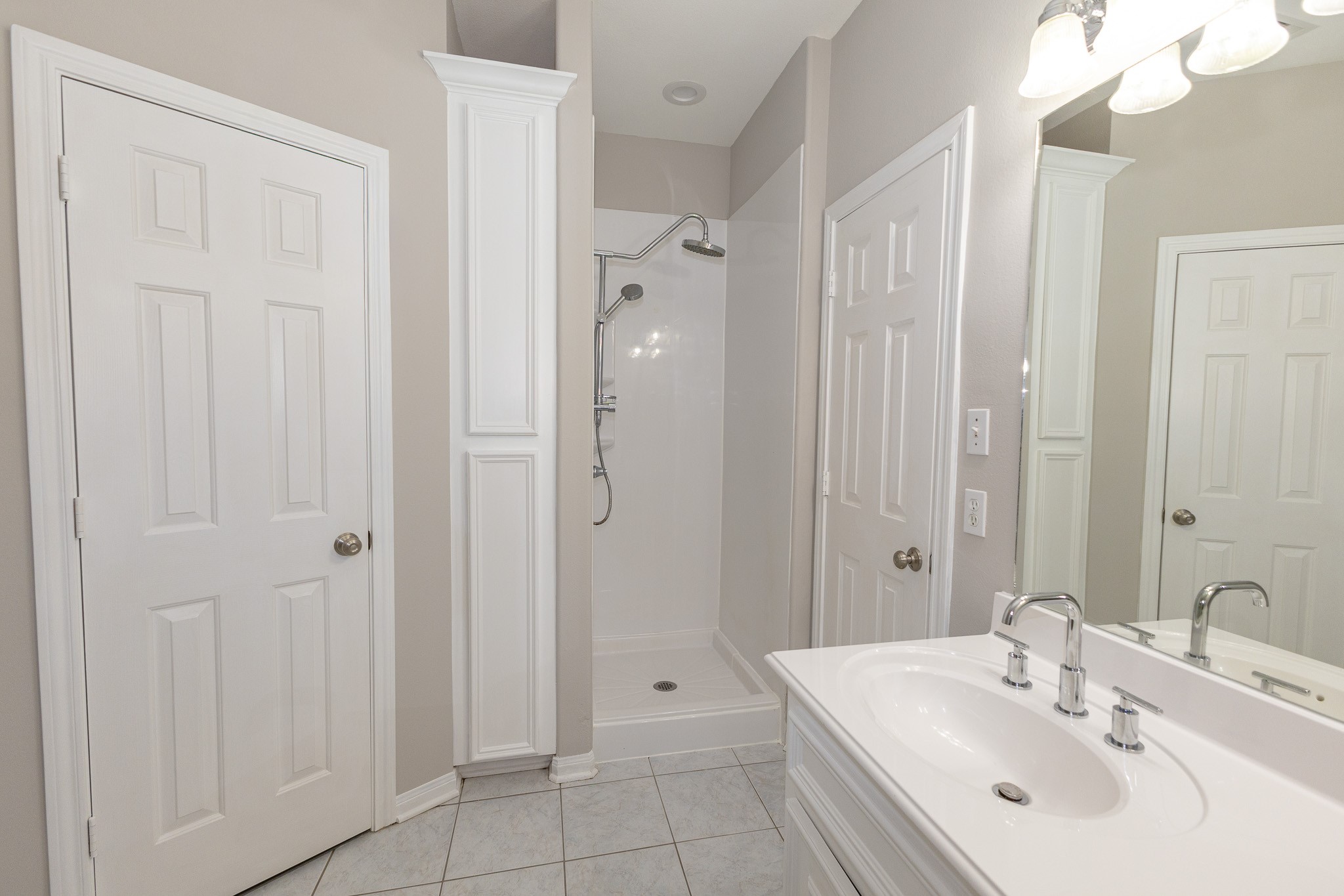 The primary bathroom offers a separate walk-in shower with dual showerheads, and built-in storage. Bright, neutral finishes create a clean, refreshing space!
