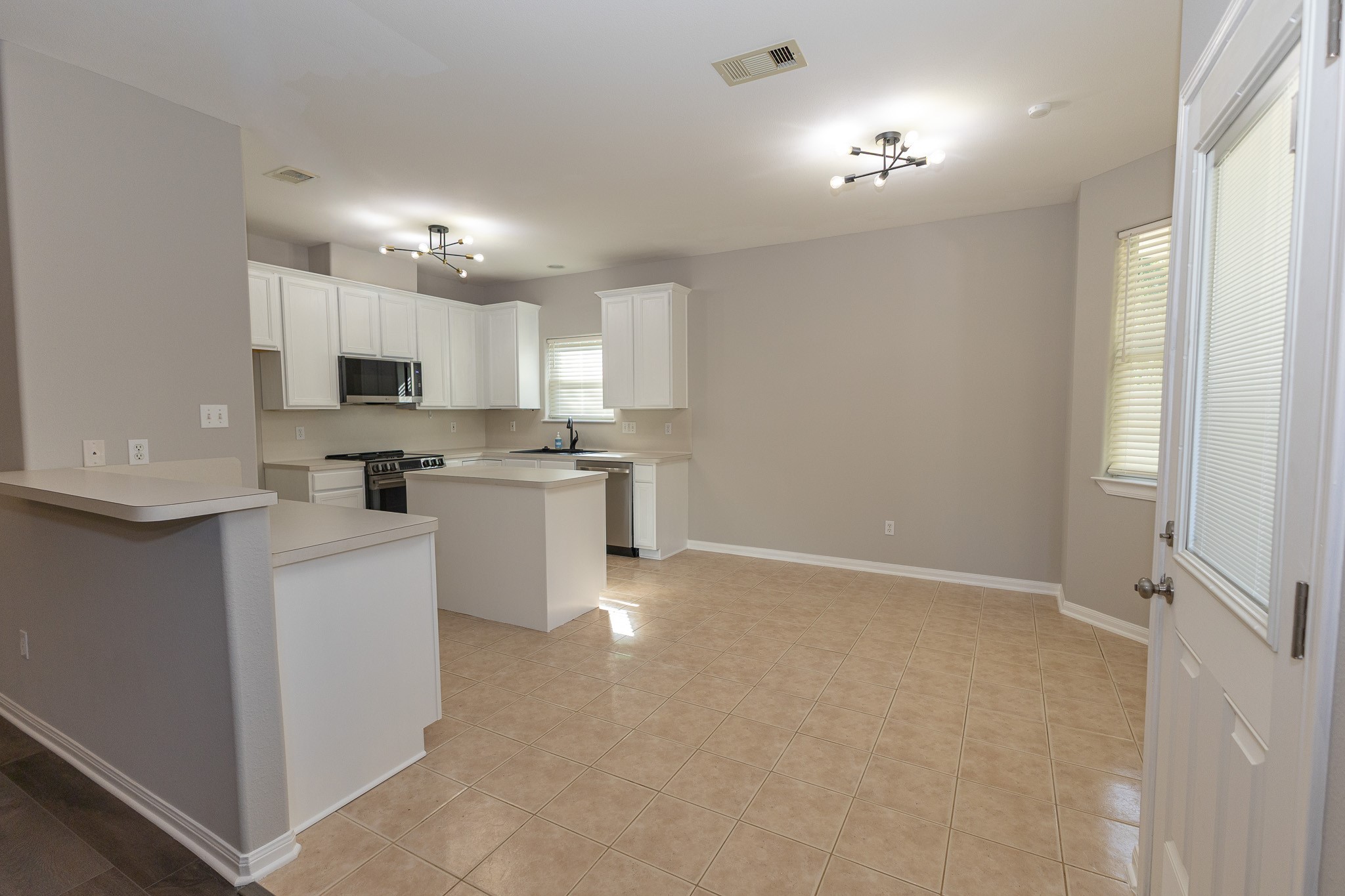 Spacious open-concept kitchen and breakfast area featuring crisp white cabinetry, modern lighting, and a convenient island. The seamless layout offers plenty of room for everyday dining, gathering, and entertaining!