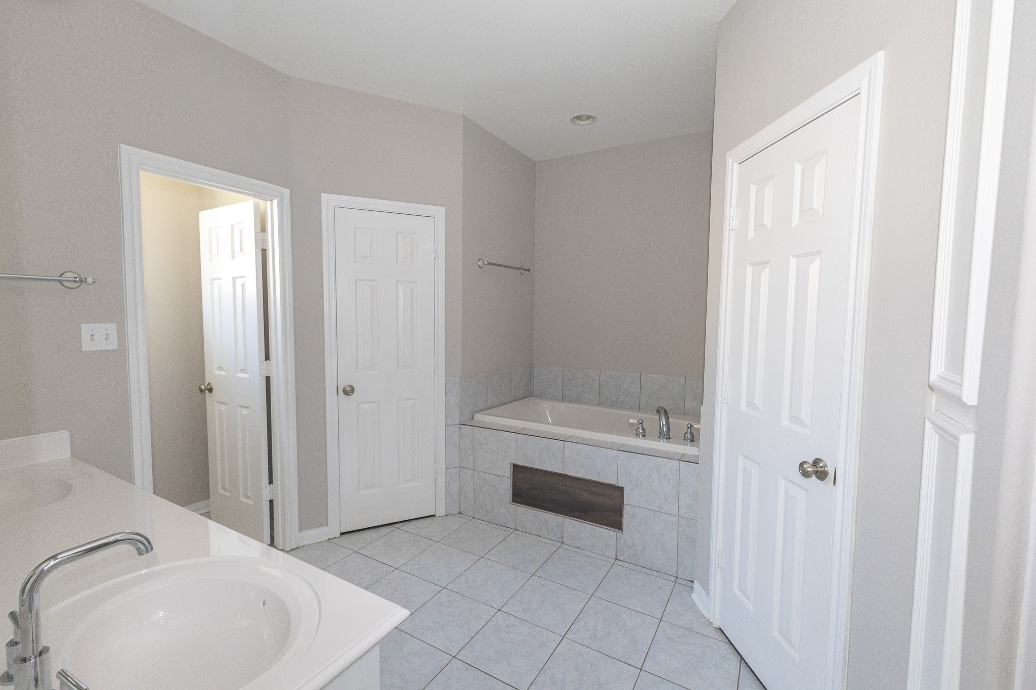 Inviting primary bathroom featuring a spacious vanity, soothing neutral tones, and a soaking tub perfect for unwinding after a long day. Thoughtfully designed with comfort and functionality in mind with his and her walk-in closets!