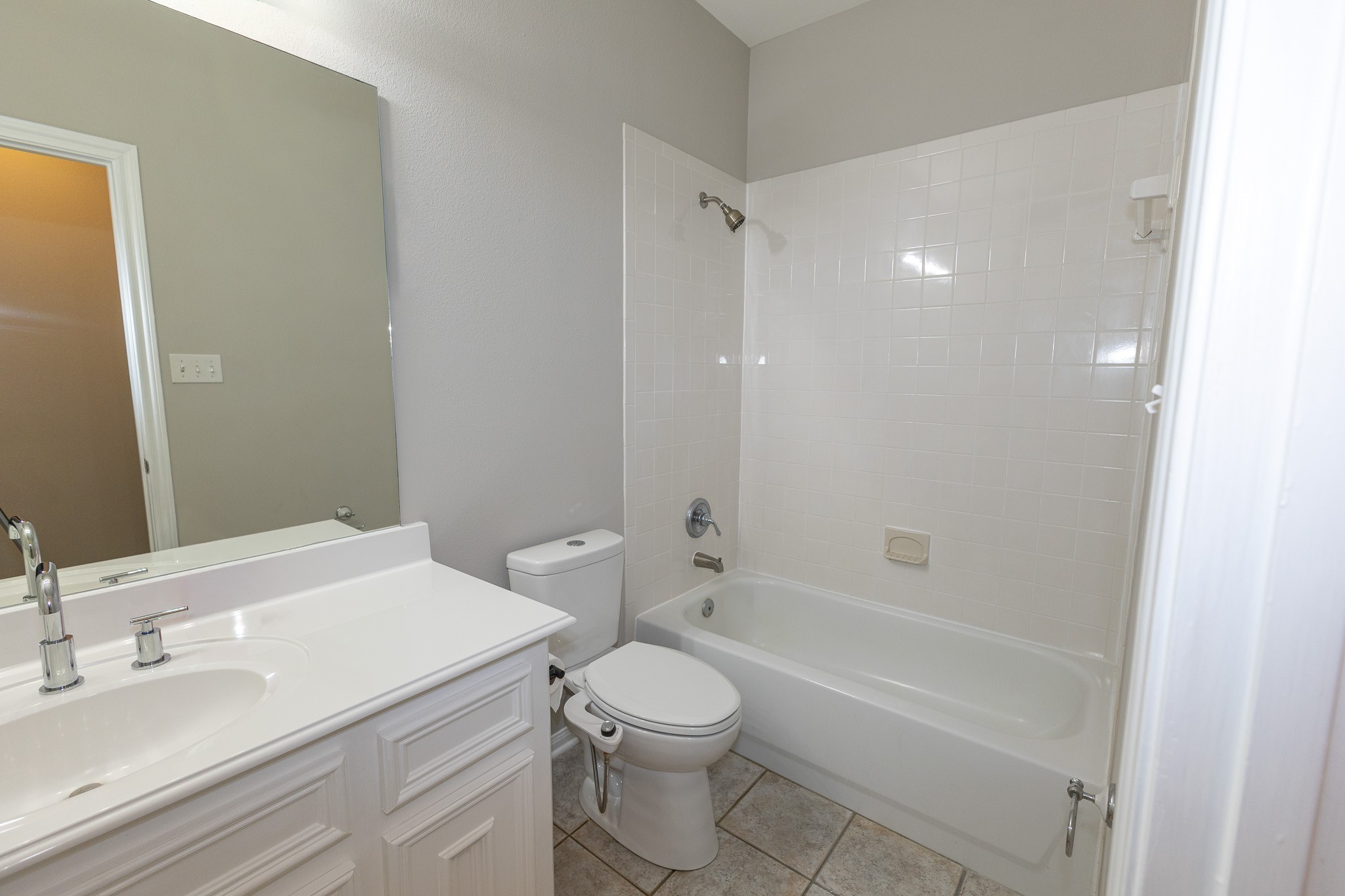 Bright and inviting guest bathroom featuring a spacious vanity, large mirror, and a tub/shower combination!