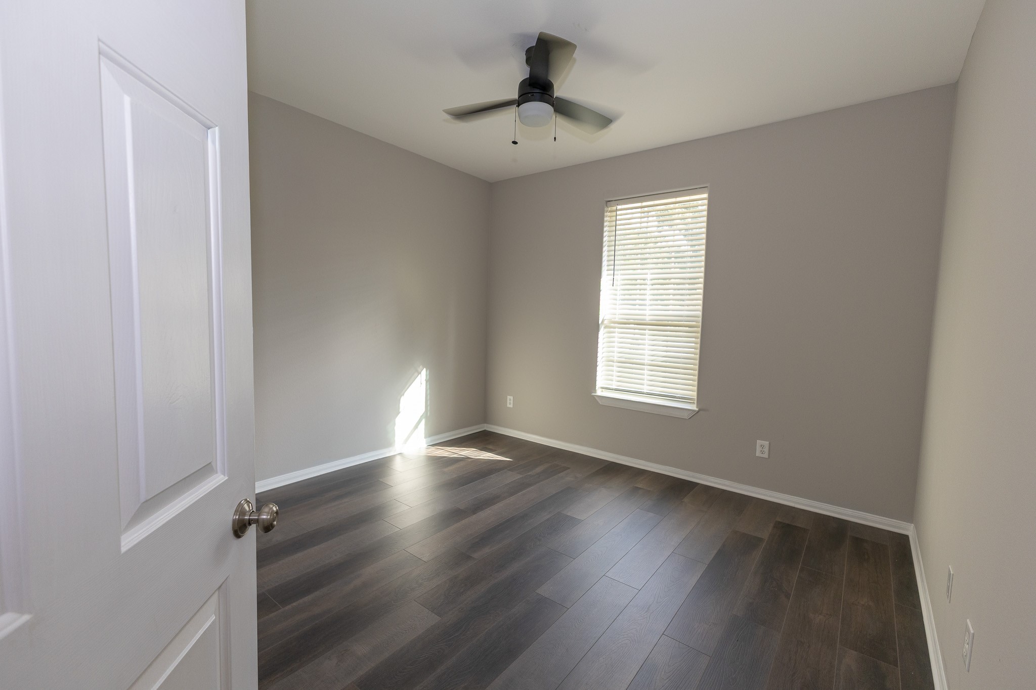 Bright and versatile second bedroom featuring beautiful new flooring, fresh neutral paint, and a modern ceiling fan. Natural light creates a welcoming space, perfect for guests, family, or a home office!