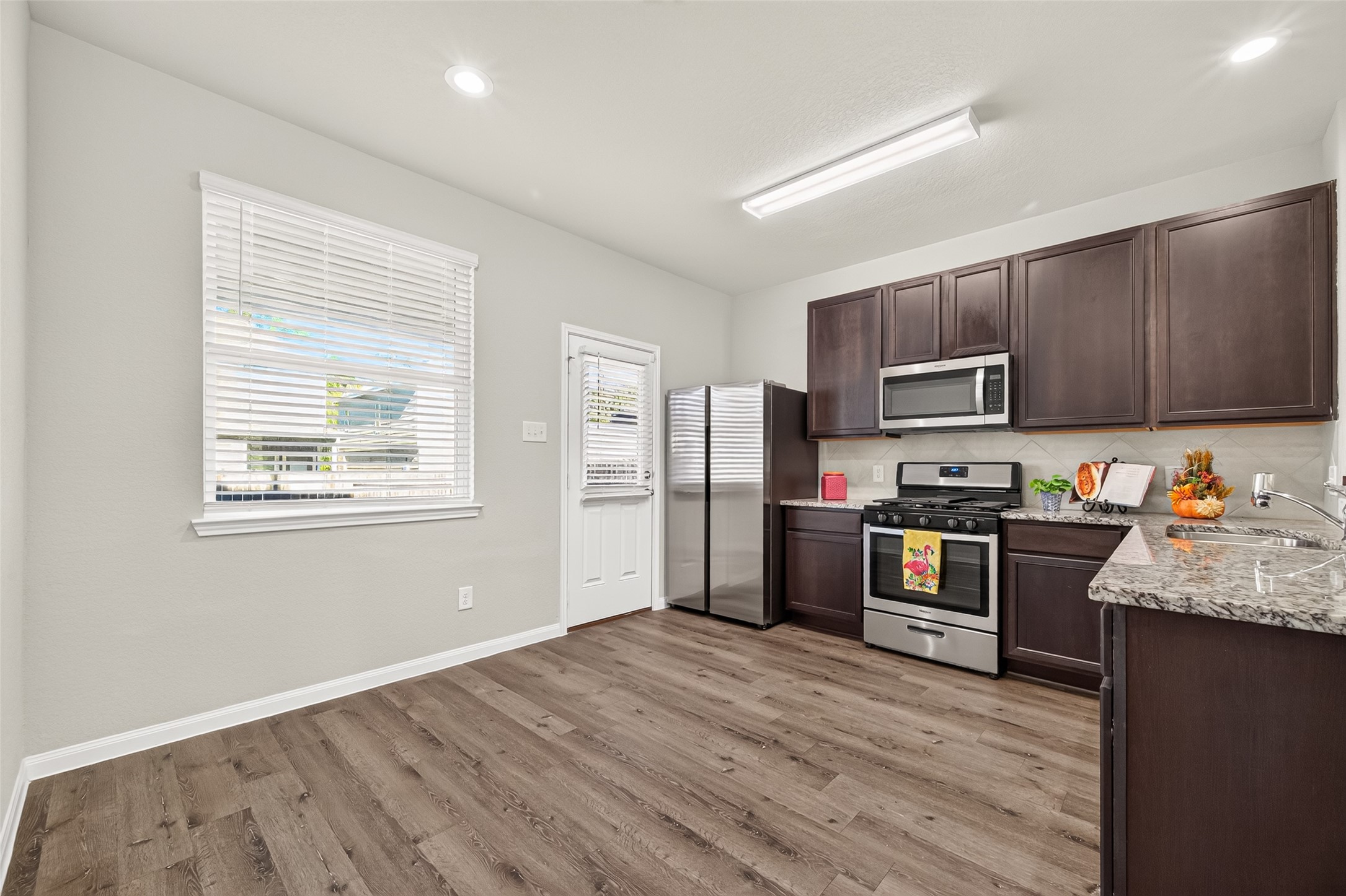 Modern kitchen with sleek stainless steel appliances, dark wood cabinetry, and elegant granite countertops, offering ample space and natural light.