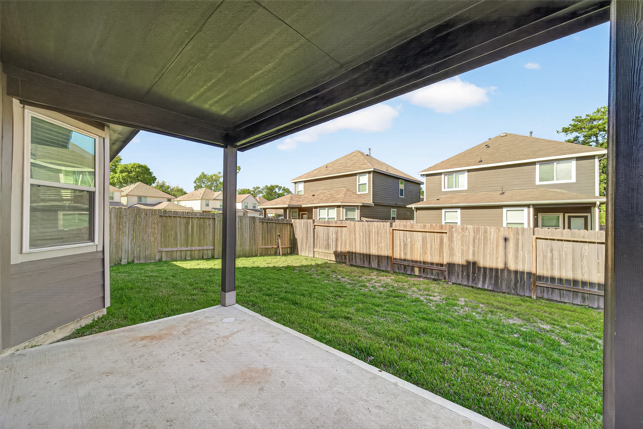 Nice size backyard with a covered patio, perfect for outdoor relaxation and entertaining, surrounded by a wooden privacy fence.