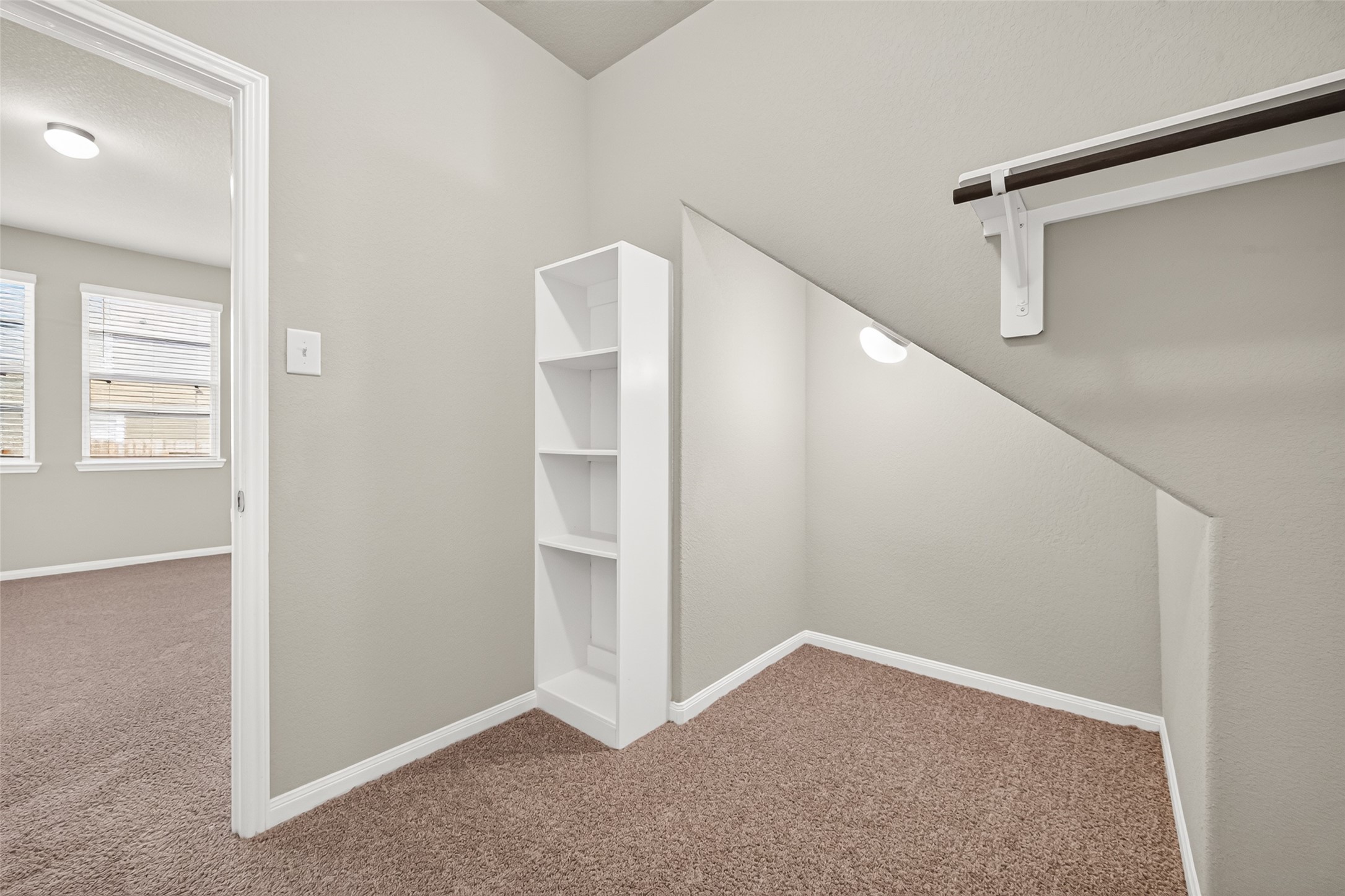 Cozy nook with built-in shelving and a hanging rod, perfect for extra storage.