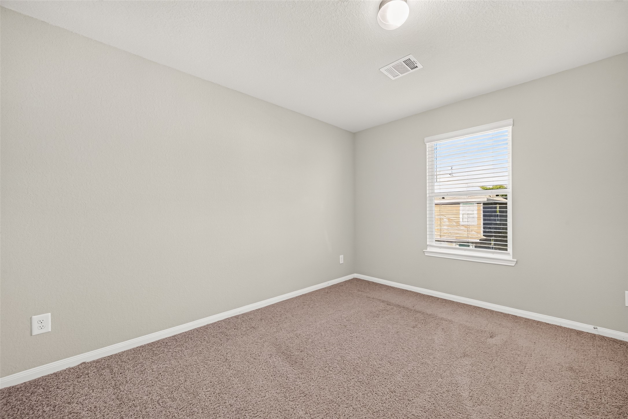 Bedroom 2 bright and airy bedroom with soft carpeting, neutral walls, and a large window for natural light.