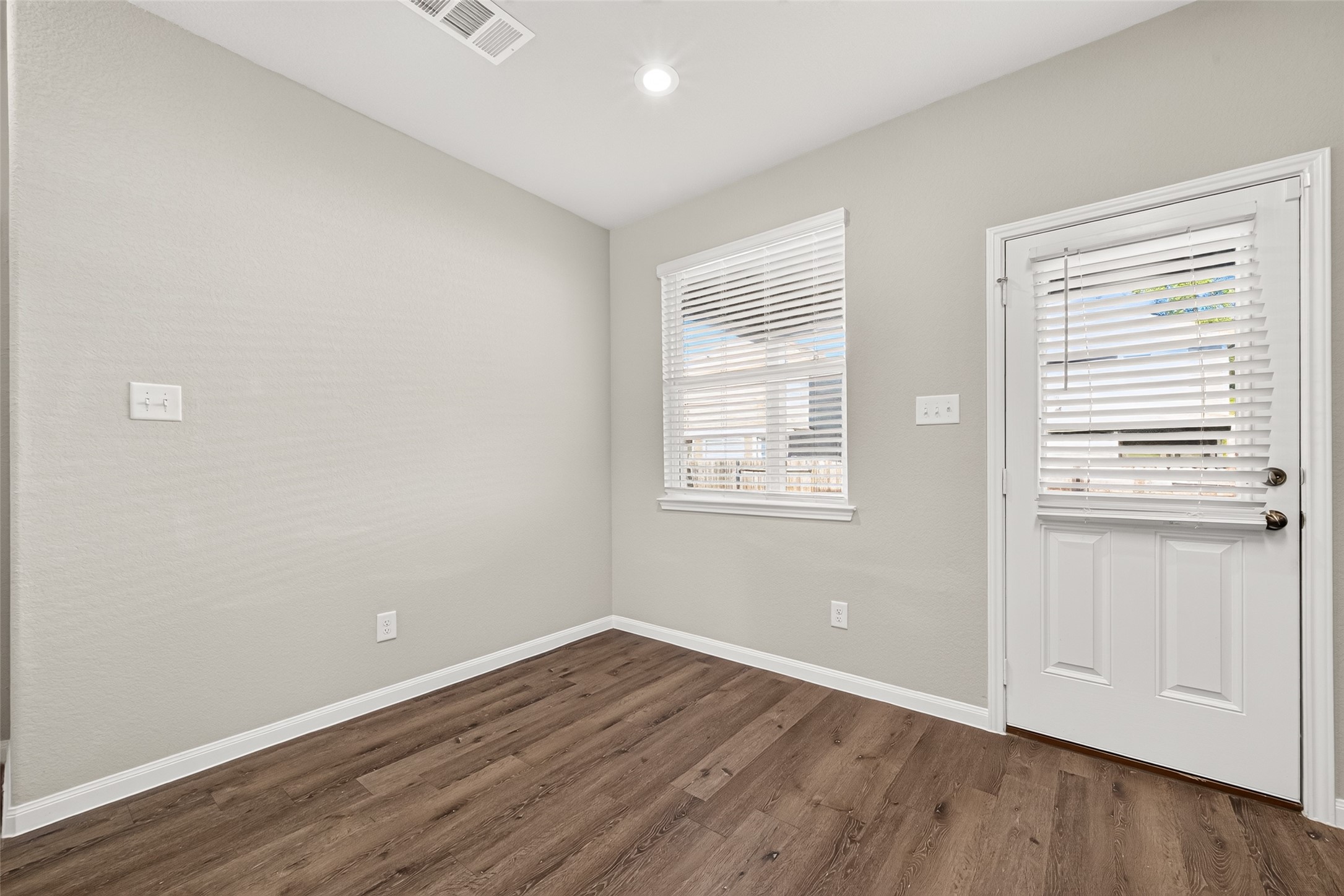 Breakfast area featuring vinyl plank flooring, neutral walls, and ample natural light through a window and glass-paneled door.