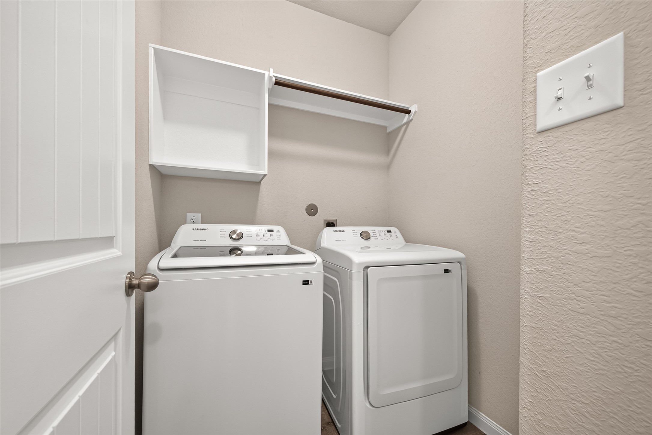 Laundry room equipped with modern Samsung washer and dryer, complemented by convenient shelving for storage.