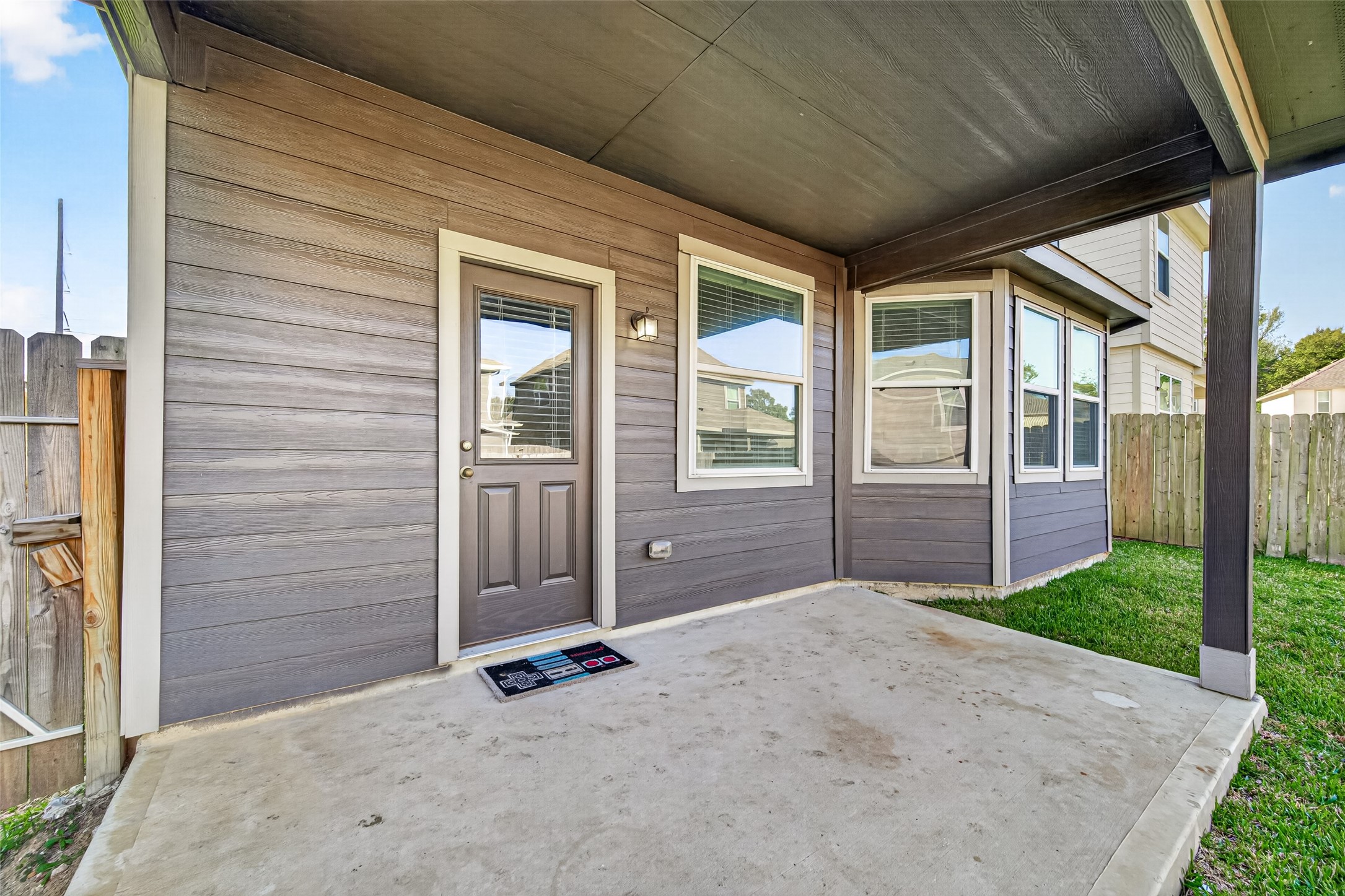 Charming covered patio area with concrete flooring, perfect for outdoor relaxation and entertainment, surrounded by a privacy fence for added seclusion.