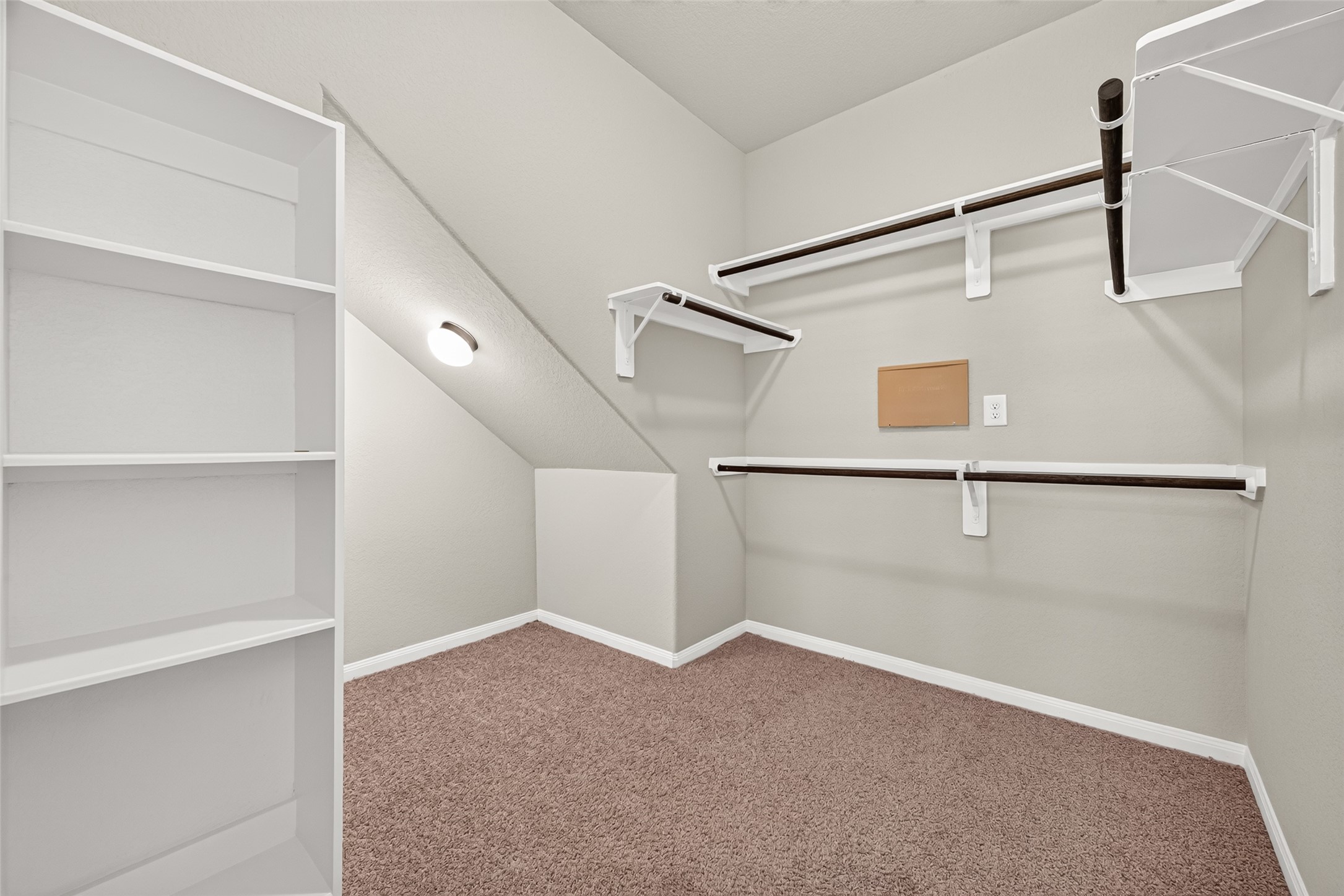 WOW look at this Spacious walk-in closet with ample shelving and hanging space, carpeted flooring, and soft lighting for a cozy and functional storage area.