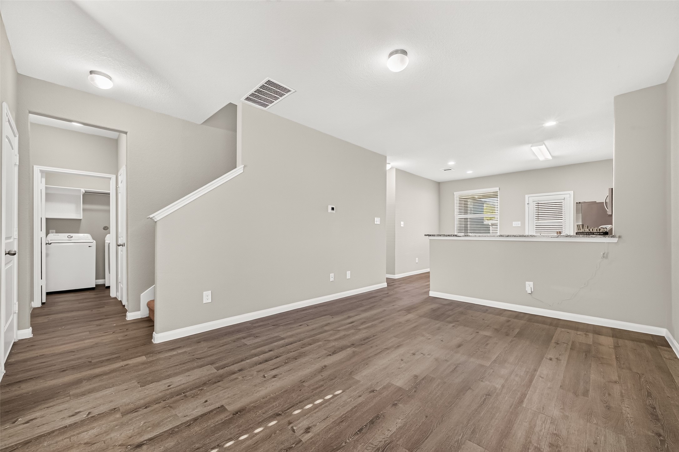 Another view of your open living space with modern vinyl flooring, and a view of your kitchen featuring a sleek breakfast bar great for entertaining.