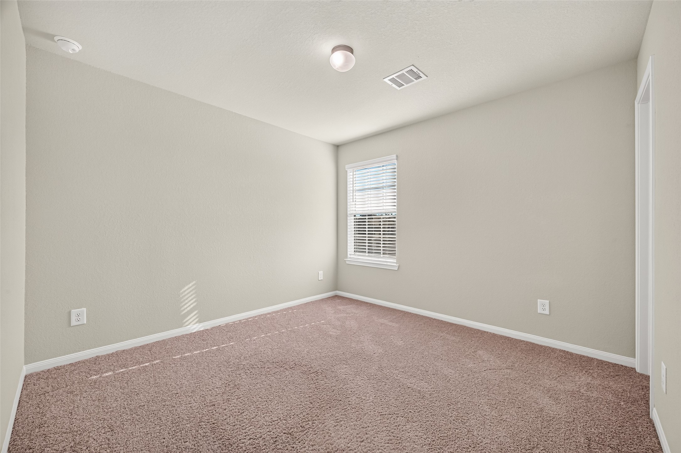 Bedroom 4 with plush carpet, neutral walls, and a bright window offering natural light.