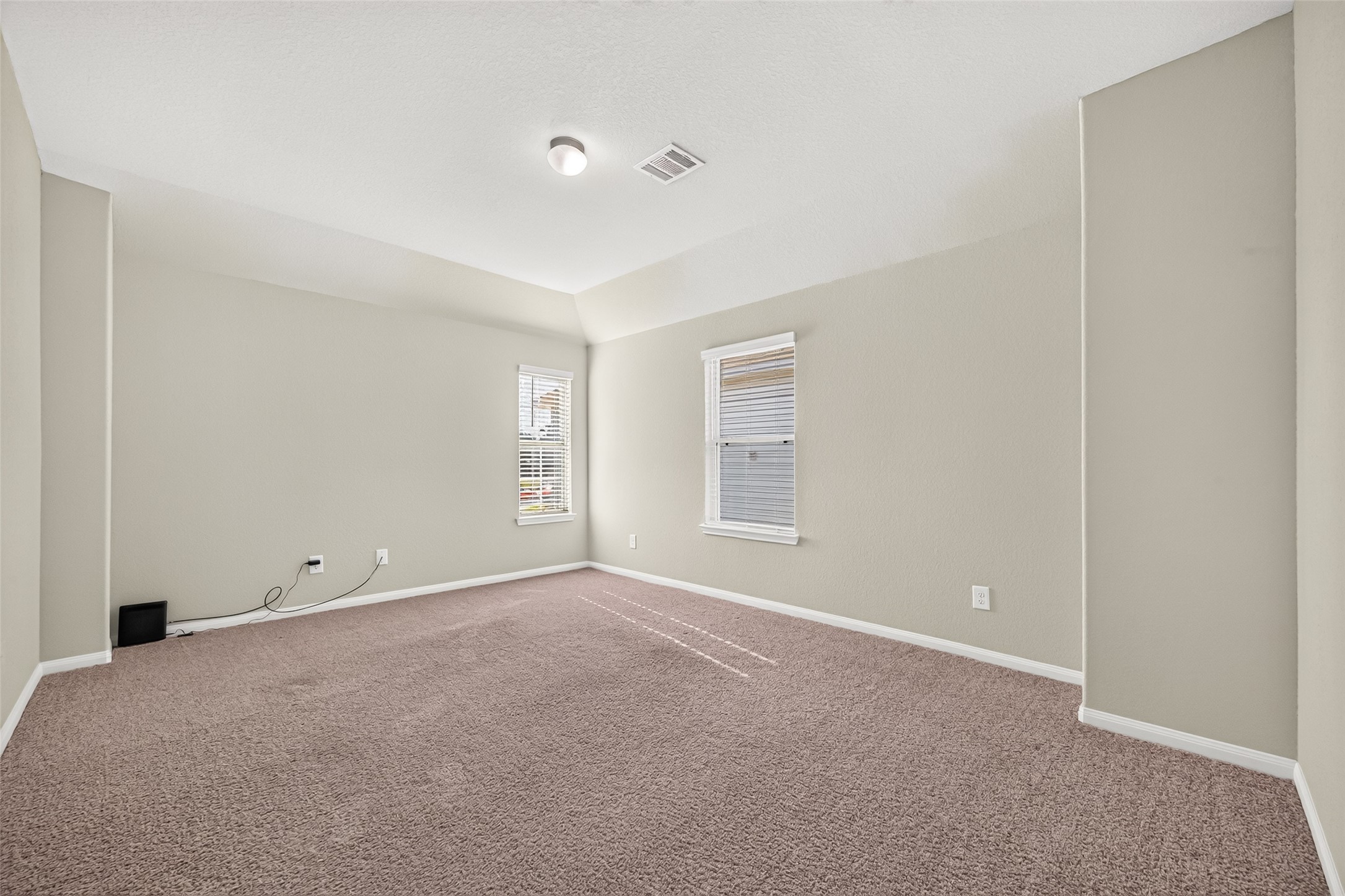HUGE game room with neutral tones, plush carpeting, and two large windows for natural light.