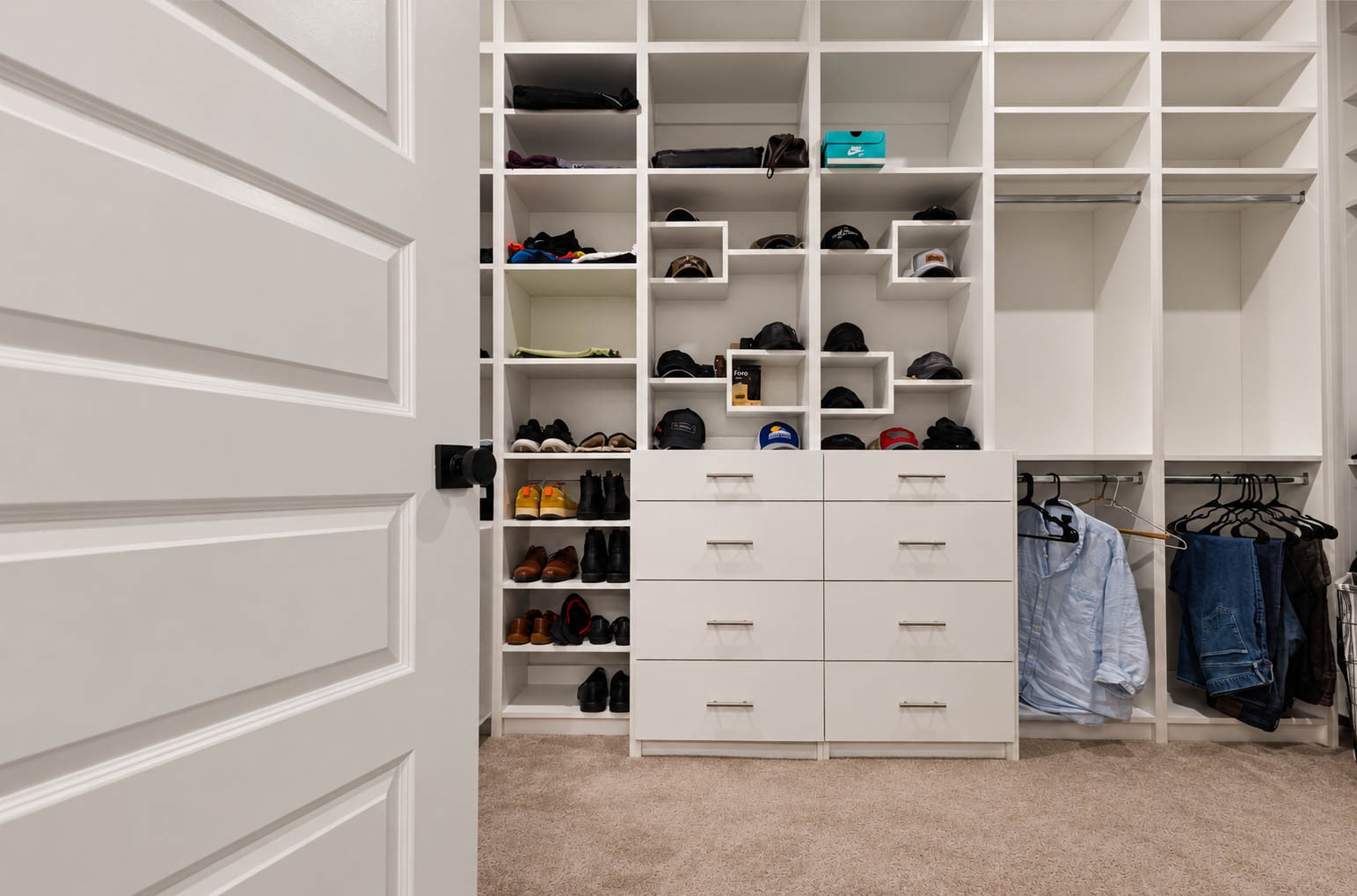 Spacious custom built walk-in closet featuring shelving, ample storage drawers, and dedicated hanging space for organized living.