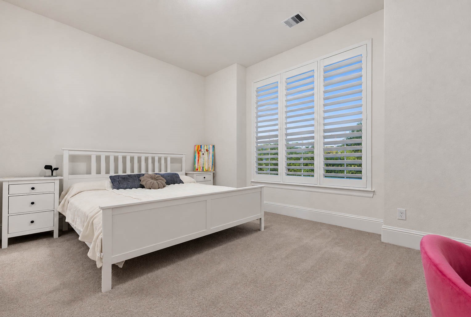 Bright and inviting bedroom at the front of the house, ample natural light from large windows with shutters, and neutral tones for a serene atmosphere.