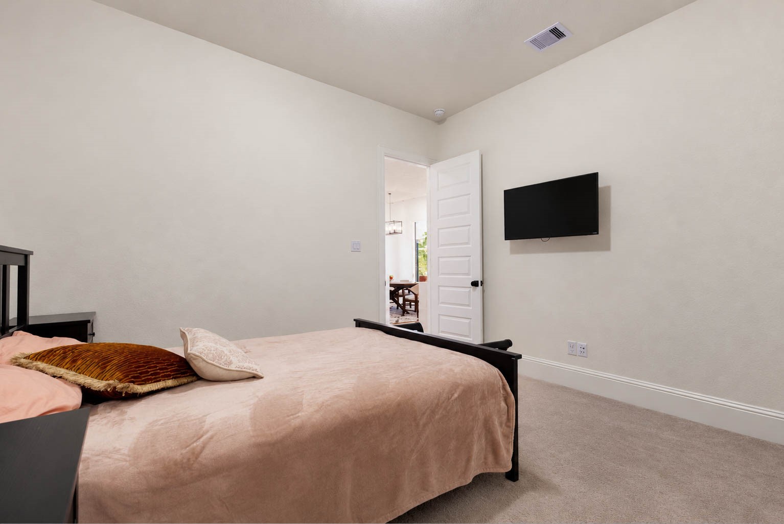 Cozy bedroom with neutral tones, featuring a wall-mounted TV and a view into the en suite bathroom.