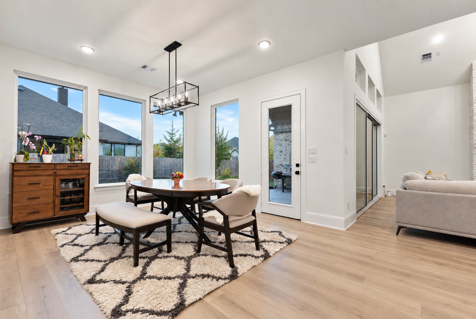 Bright and inviting dining area featuring large windows, a modern chandelier, and seamless flow into the living space, perfect for entertaining.