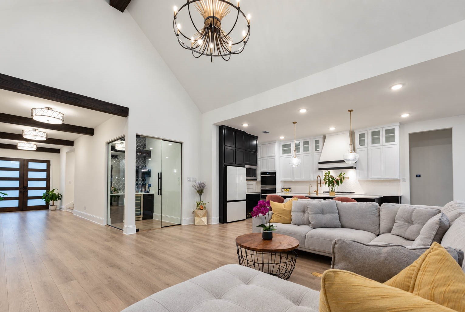 Spacious open-concept living area with vaulted ceilings, featuring a modern kitchen with sleek cabinetry and a large island, complemented by a stunning wine bar to add that wow factor.