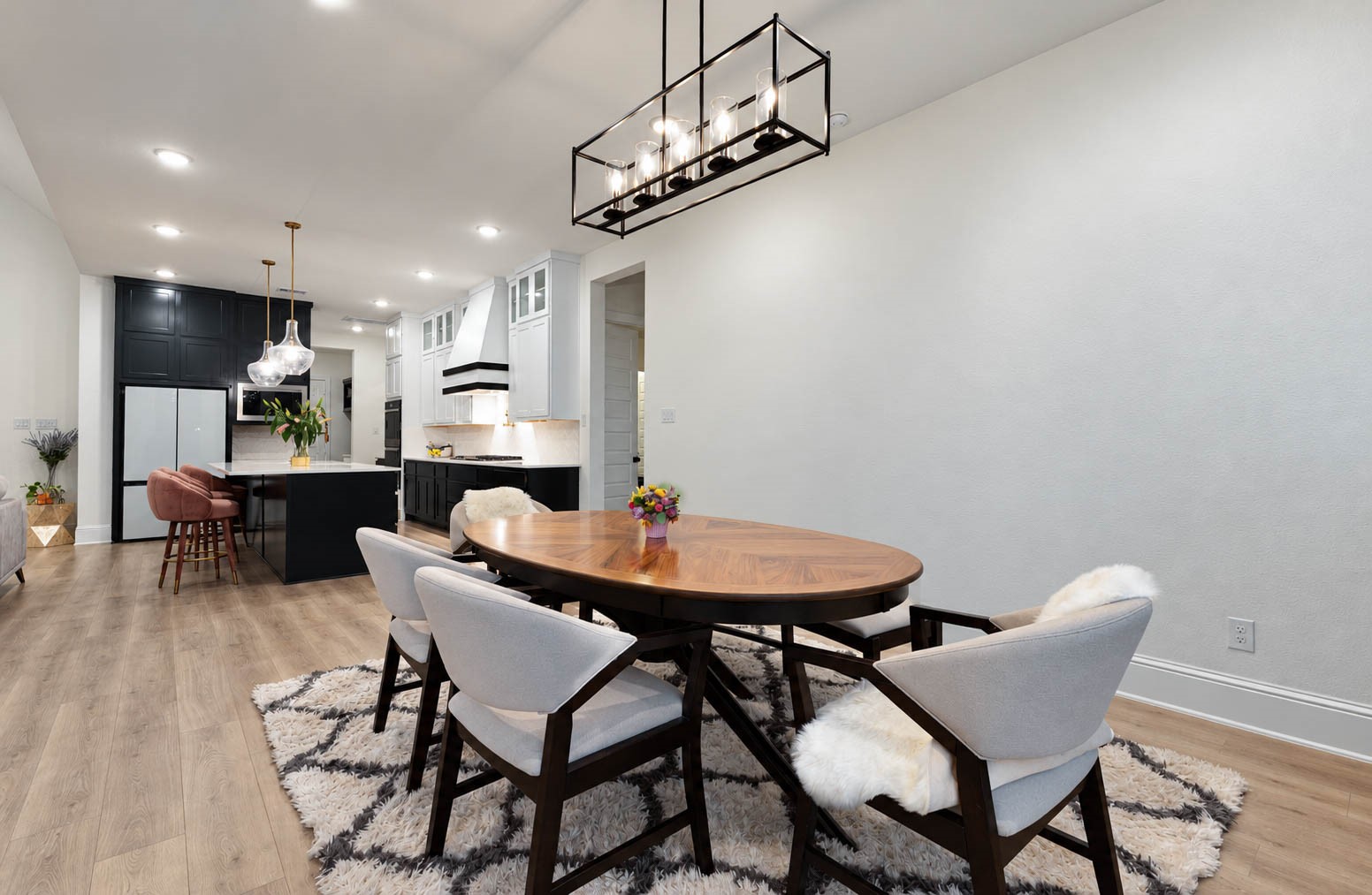 Bright and spacious open-concept dining area with modern fixtures,  flowing into a chic kitchen with a large island and contemporary lighting.