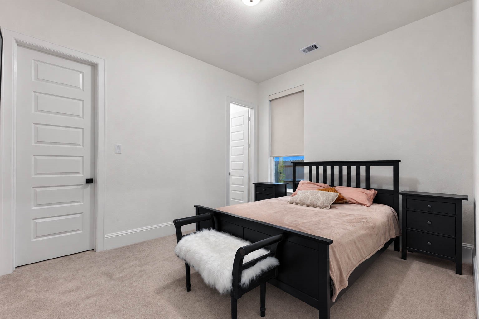 Cozy bedroom with neutral tones with soft carpeting for a welcoming atmosphere.