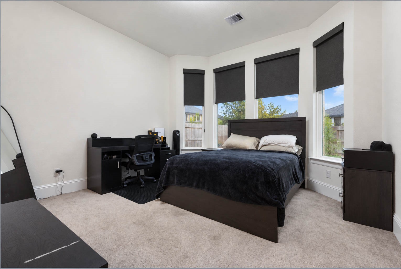 Spacious bedroom with large windows with shades, offering ample natural light. Complemented with an in suite bathroom
