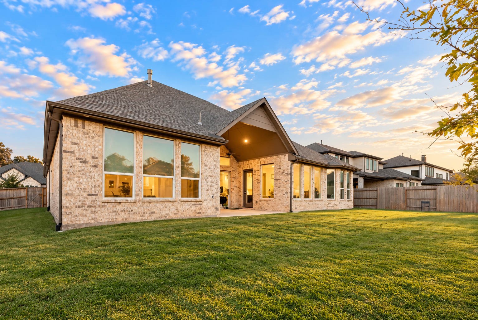 Charming brick home with expansive windows and a spacious backyard, perfect for enjoying sunsets and outdoor gatherings.
