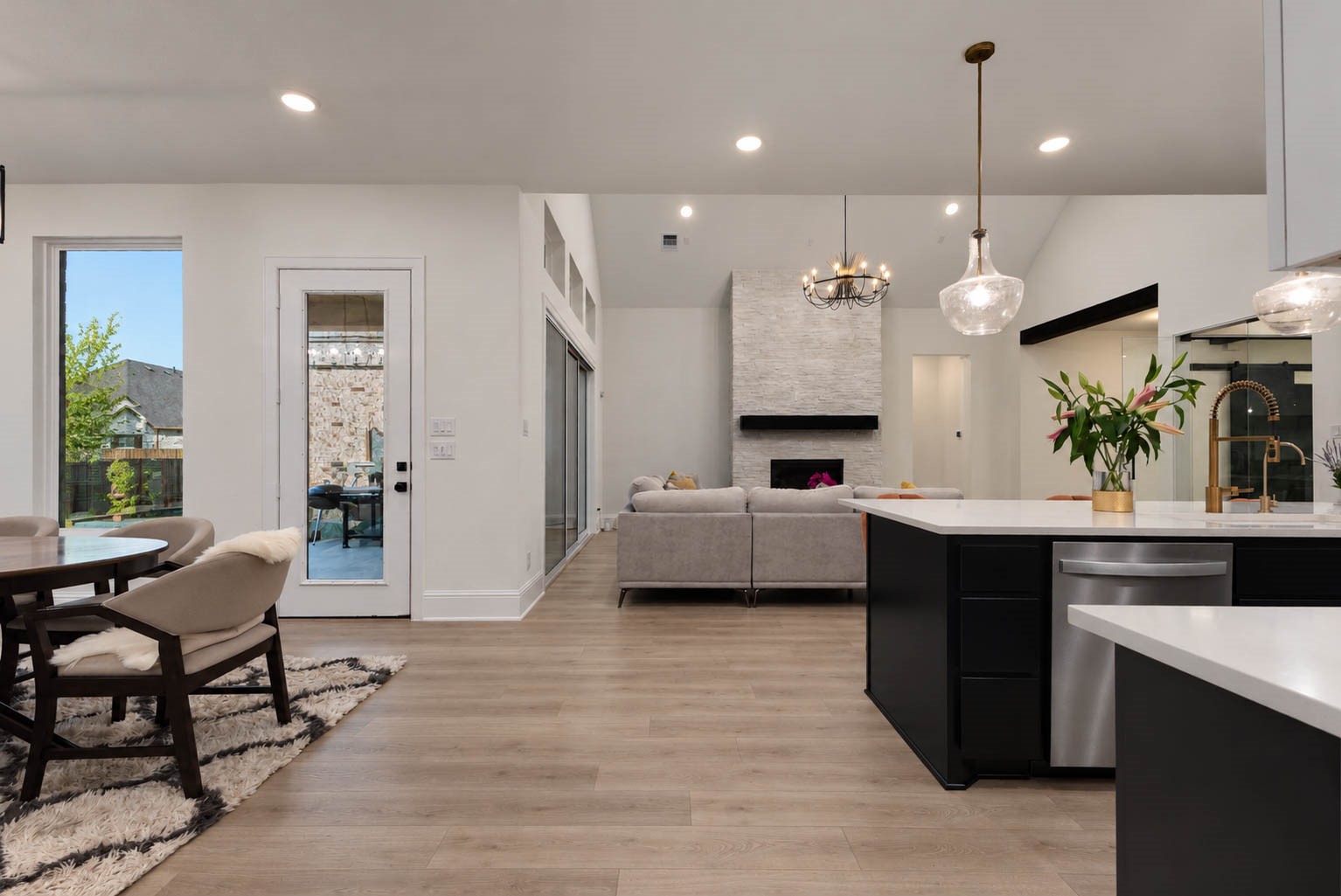 Stunning open-concept living space featuring a modern kitchen with sleek countertops, elegant pendant lighting, and a cozy living area with a stylish fireplace. Perfect for entertaining and relaxation.