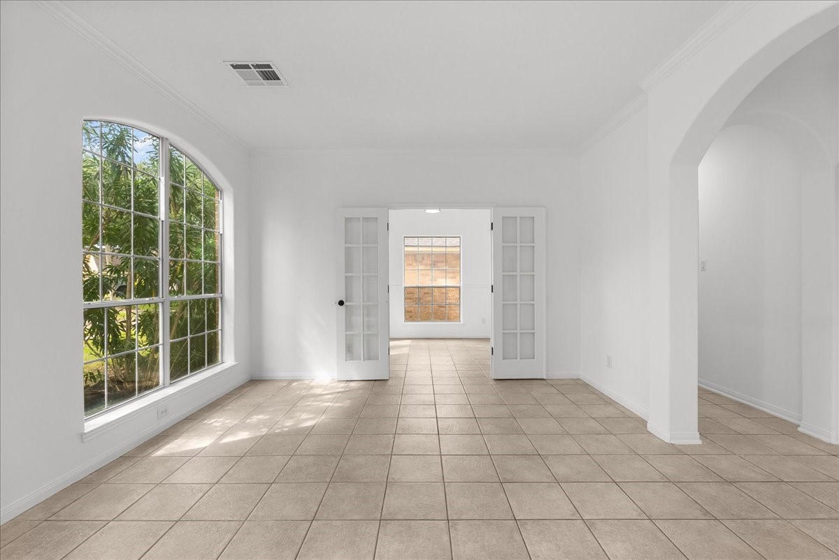 Formal living room with a large arched window and French doors leading to the study/bedroom.