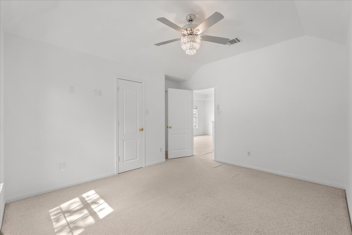 This bedroom has a vaulted ceiling and beautiful crystal light fixture/fan combo and an attached en-suite bathroom.