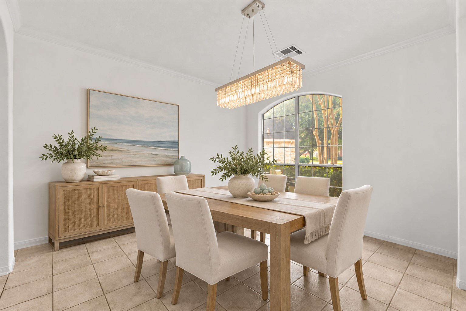 Spacious Formal dining room with a crystal chandelier and arched window. Virtually staged.