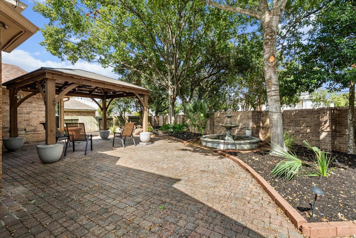Paver patio with an oversized pergola and tiered fountain, perfect for relaxing or entertaining outside.