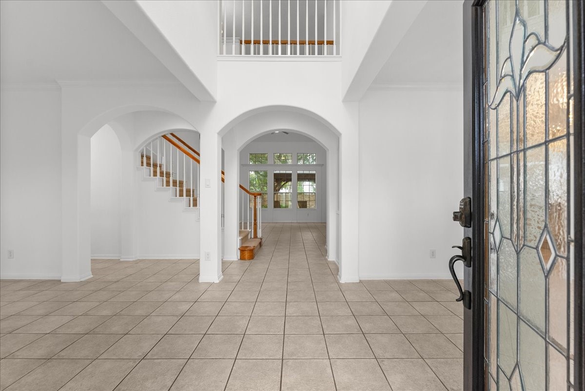Two-story entry with a stained glass front door, arched openings.