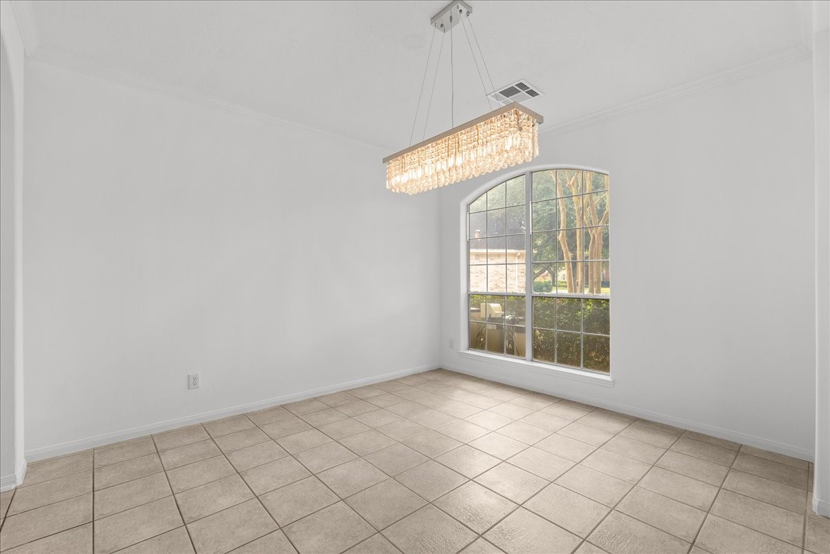 Spacious Formal dining room with a crystal chandelier and a tall arched window.