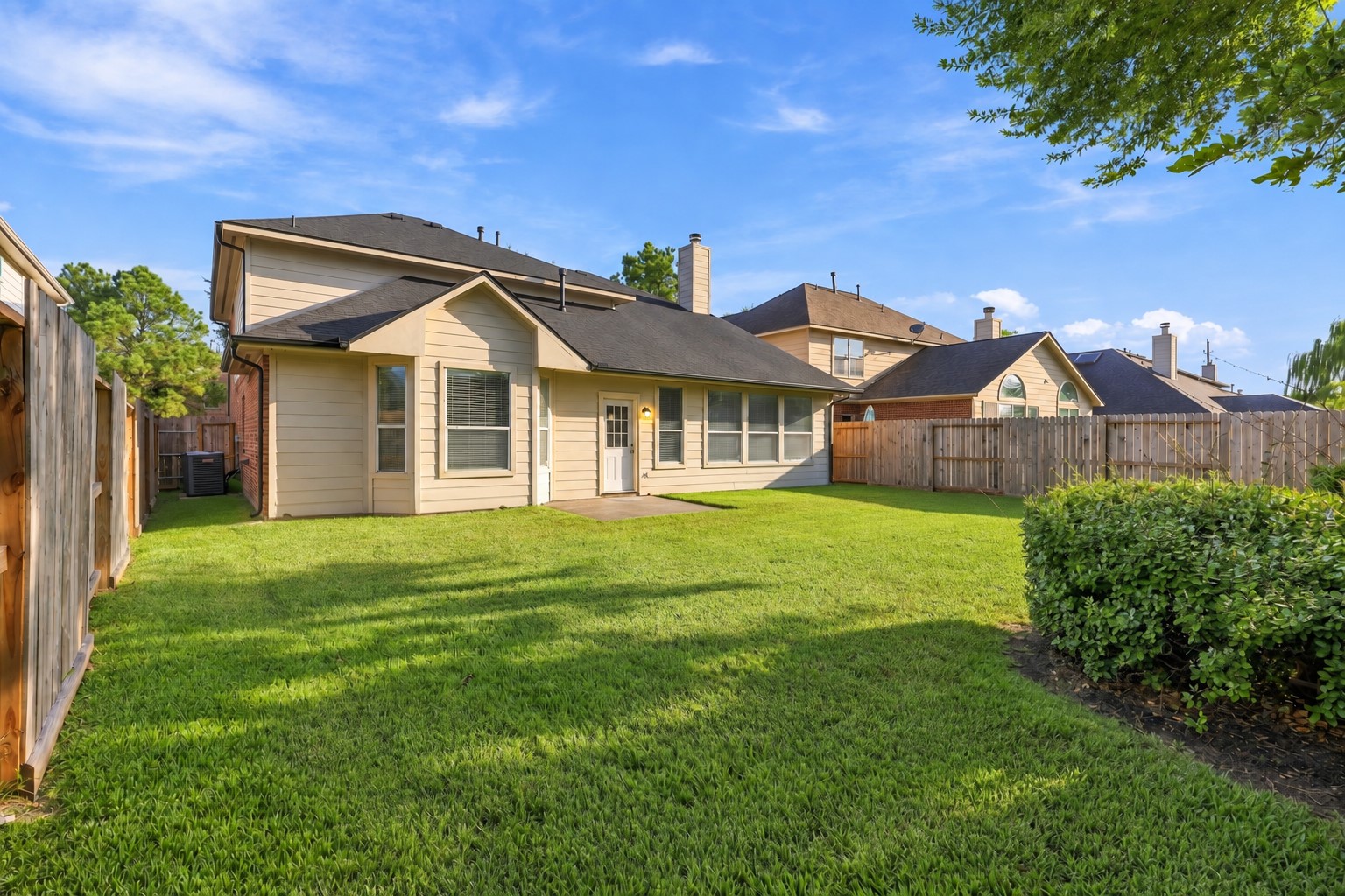 Another view of the generous private backyard showcases the expansive grassy area, mature landscaping, privacy fencing, and surrounding greenery. Plenty of outdoor space offers endless possibilities for entertaining, recreation, and creating your own backyard retreat.