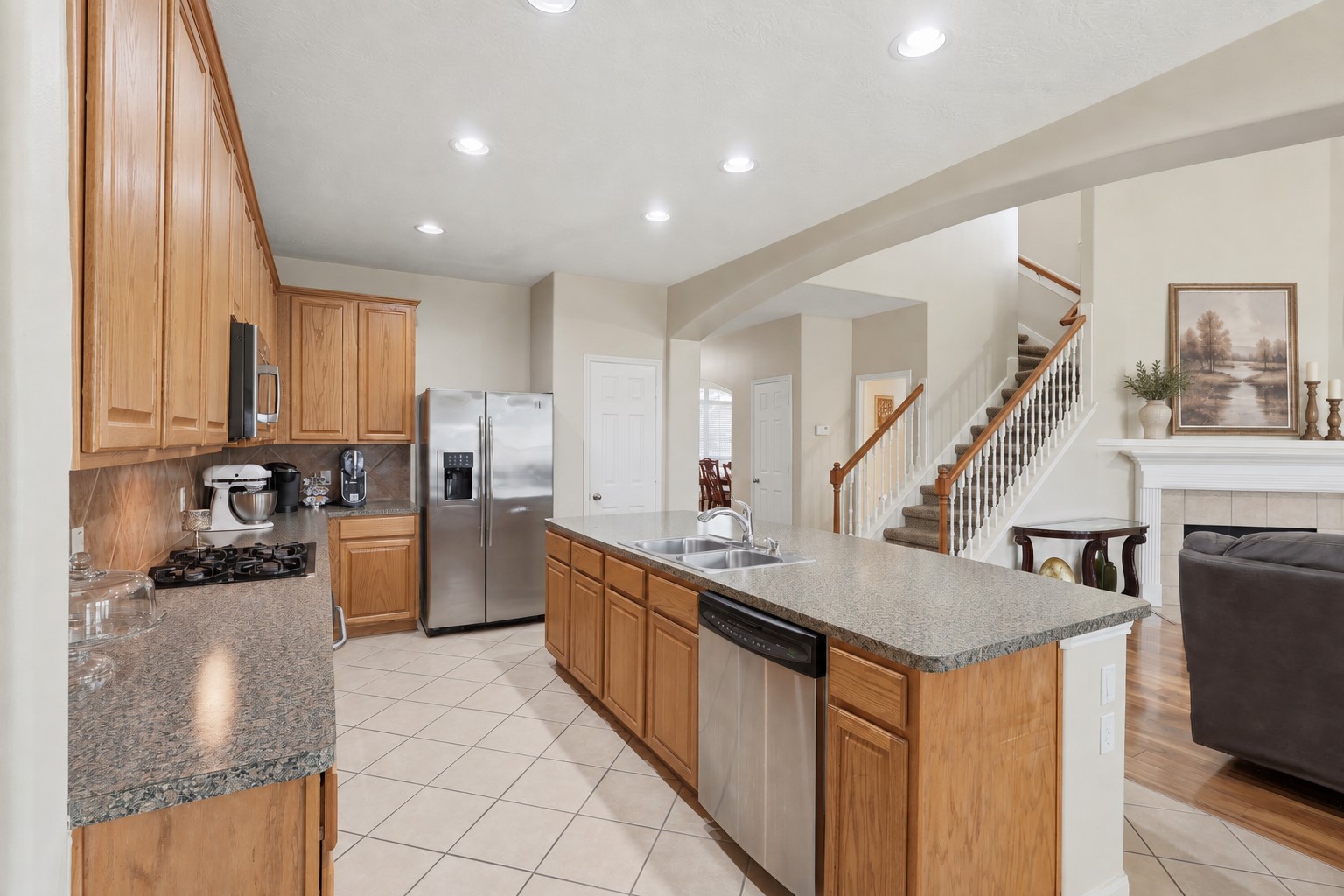 Spacious kitchen featuring abundant cabinetry and counter space, built-in stainless steel appliances, a tile backsplash, a large center island, and bright recessed lighting. The open layout facilitates both meal preparation