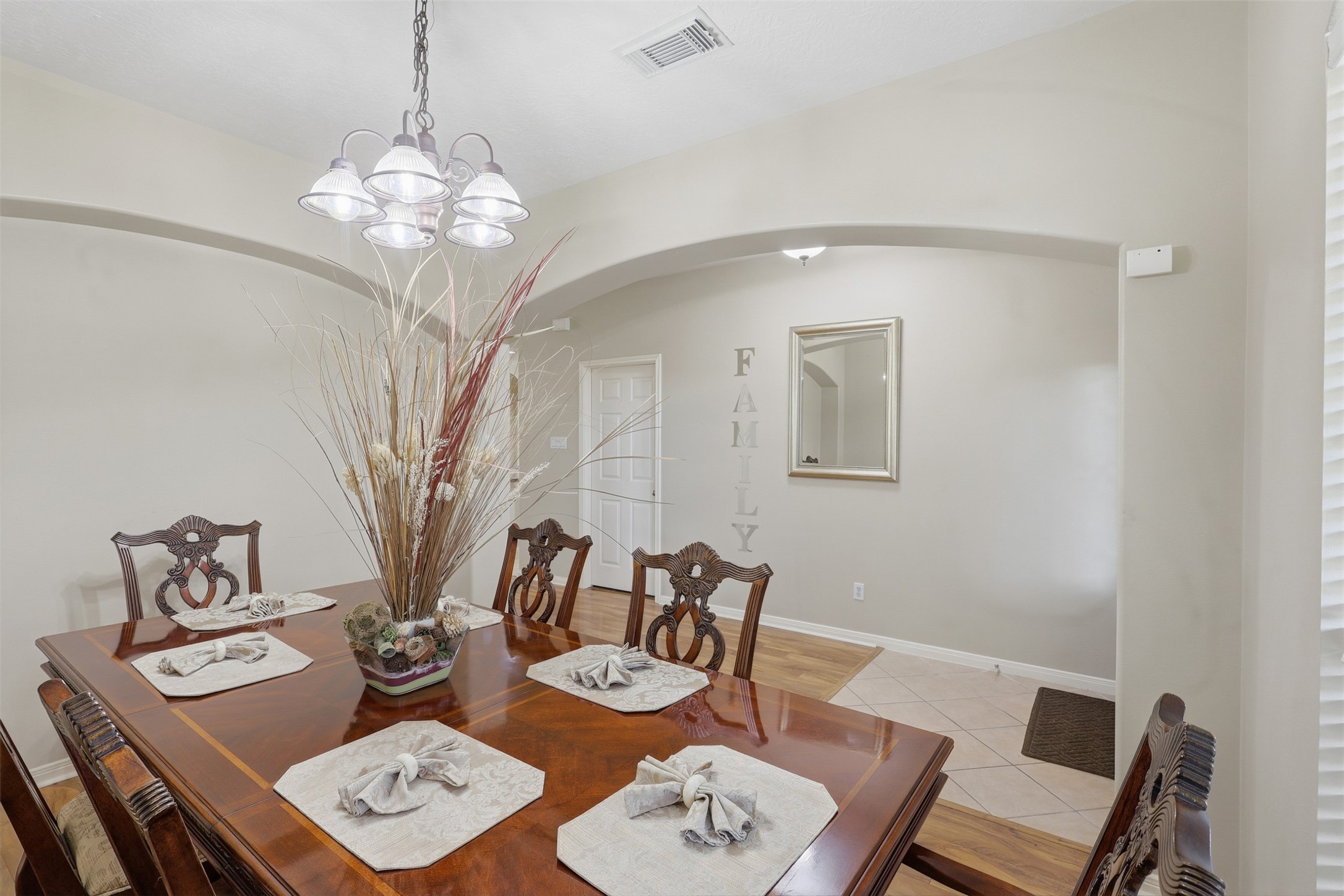 Spacious and welcoming, the formal dining room offers plenty of room for family dinners and entertaining. Elegant arched details, beautiful wood-look flooring, and a decorative chandelier add timeless character, while the open layout provides an effortless connection to the entry.