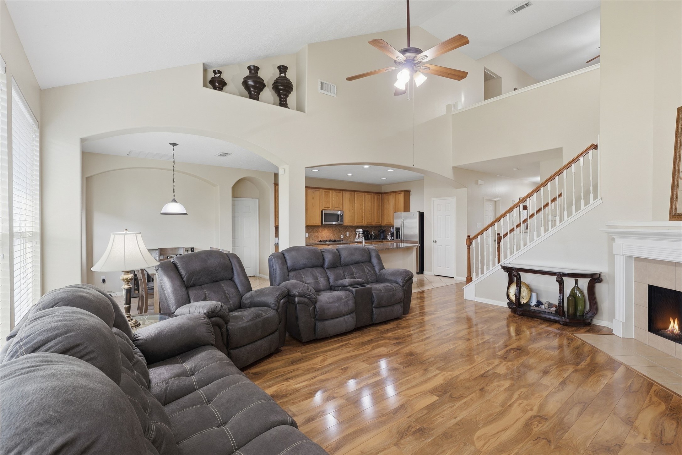 Spacious two-story family room offers an impressive open layout with soaring ceilings, beautiful wood-look flooring, a cozy corner fireplace, and a wall of windows that fills the space with natural light. The open connection to the kitchen makes entertaining effortless.  Timeless floor plan!