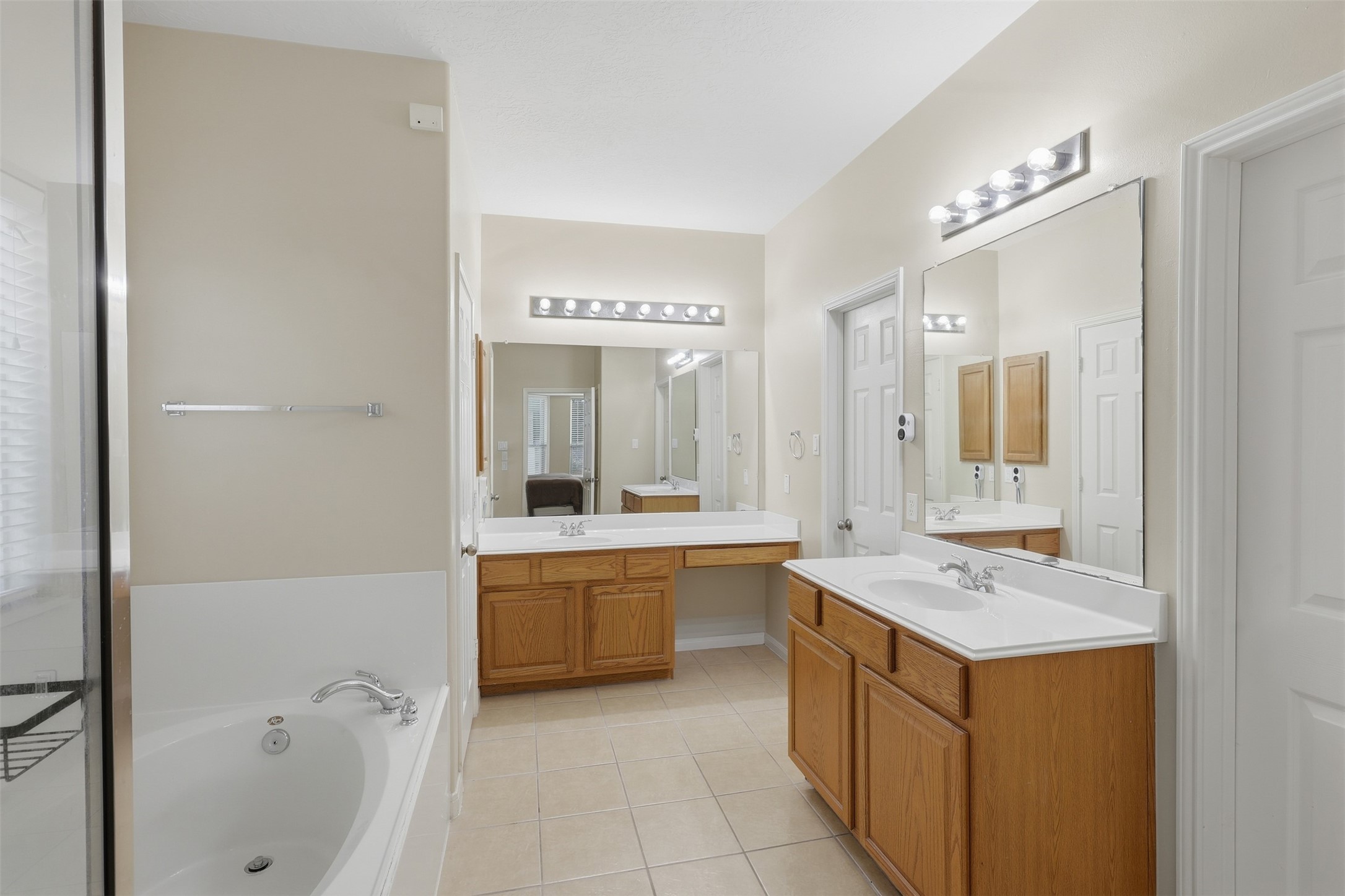 Beautiful primary bath offers a spa-like retreat with dual private vanities, generous cabinetry, large mirrors, soaking tub, and separate walk-in shower. Bright lighting and a spacious layout create a comfortable and relaxing start or end to your day.