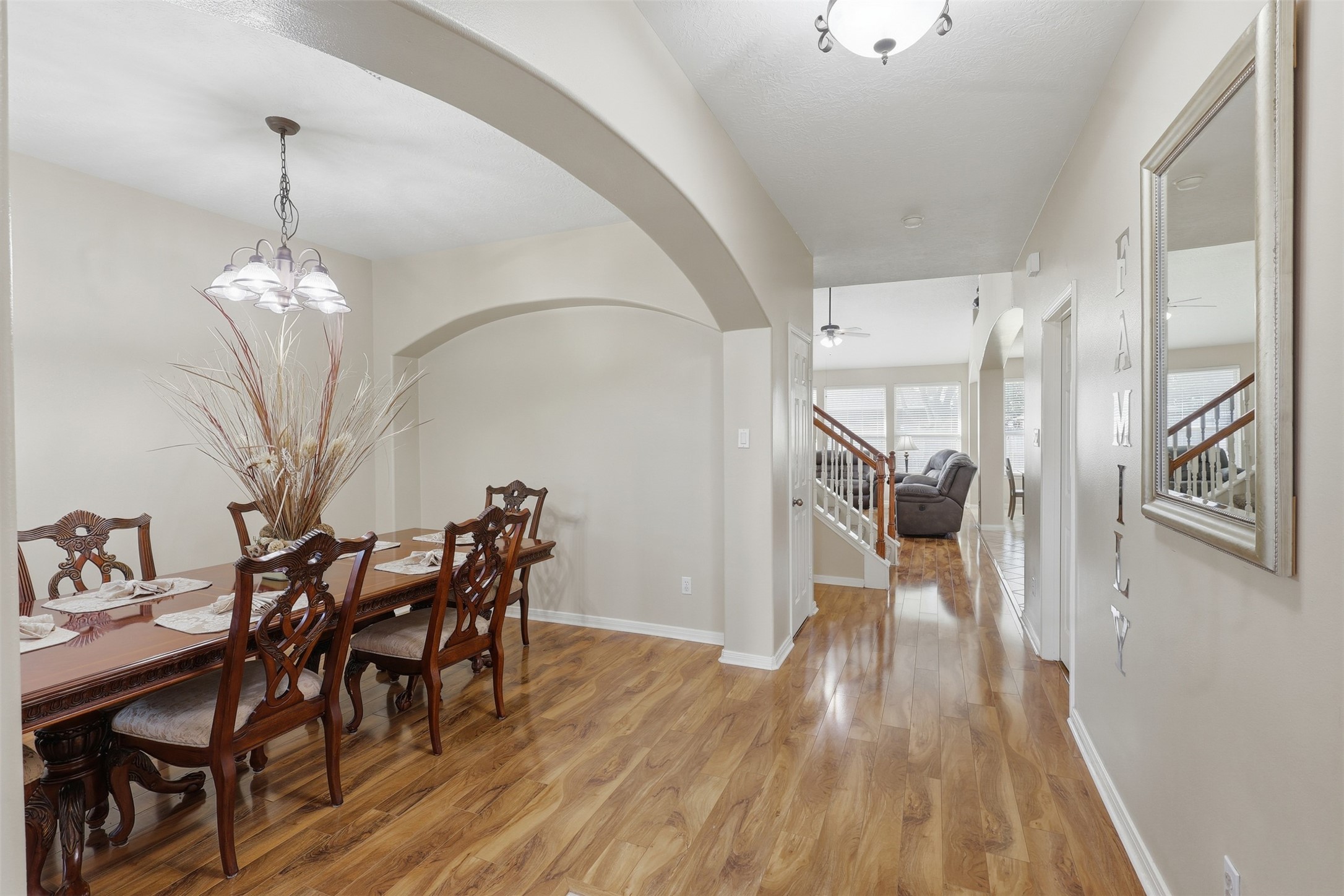 A beautiful first-floor view showcasing the home's welcoming entry and elegant formal dining room. Arched architectural details, soaring ceilings, wood-look flooring, and abundant natural light create an open and inviting introduction to the home, with easy flow toward the main living areas.