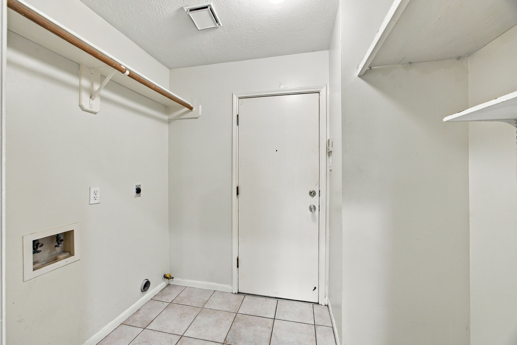 A dedicated laundry room includes washer and dryer connections, open shelving, and a hanging rod for added convenience.