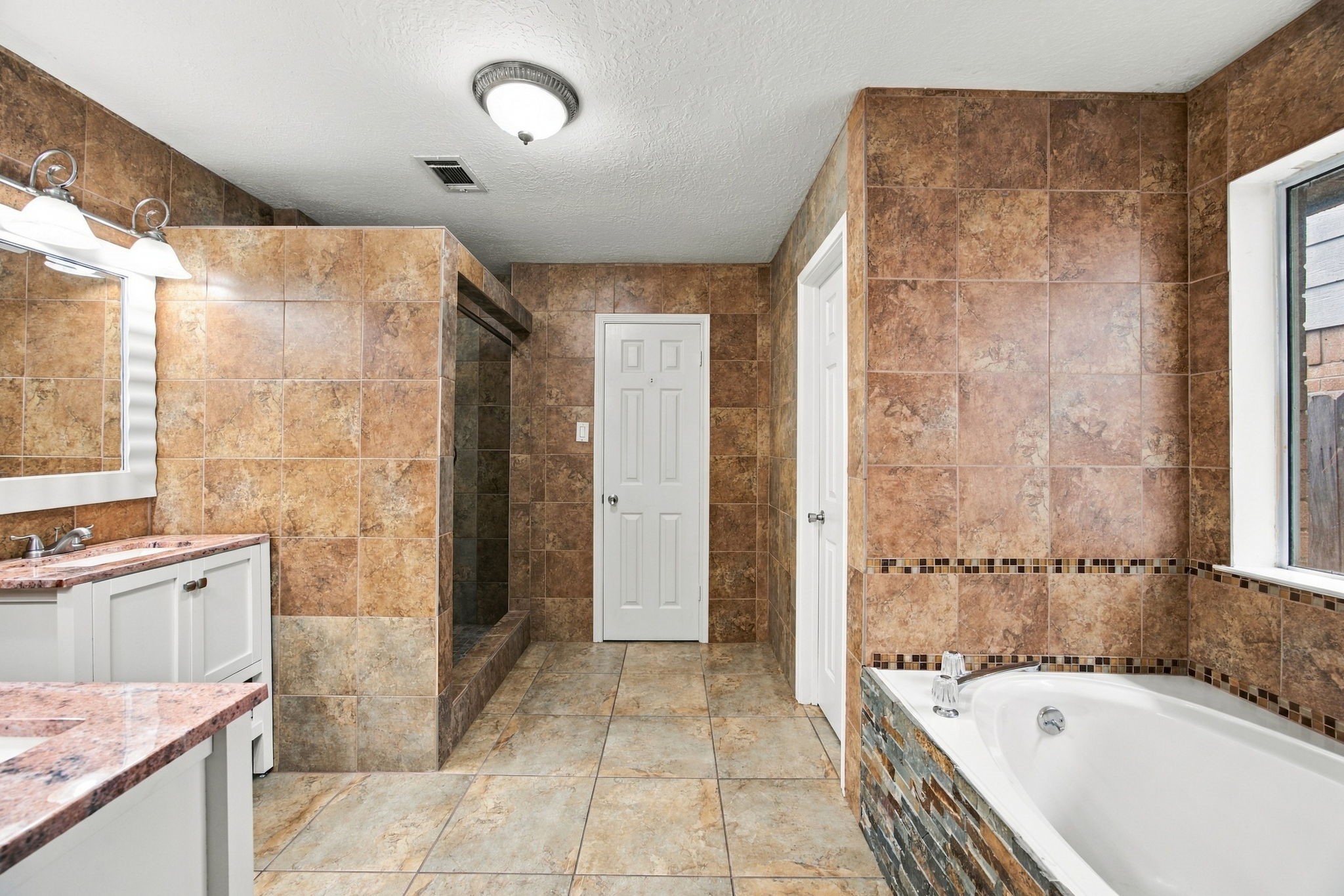 Warm tile surrounds a primary bath with a soaking tub and a separate walk-in shower.