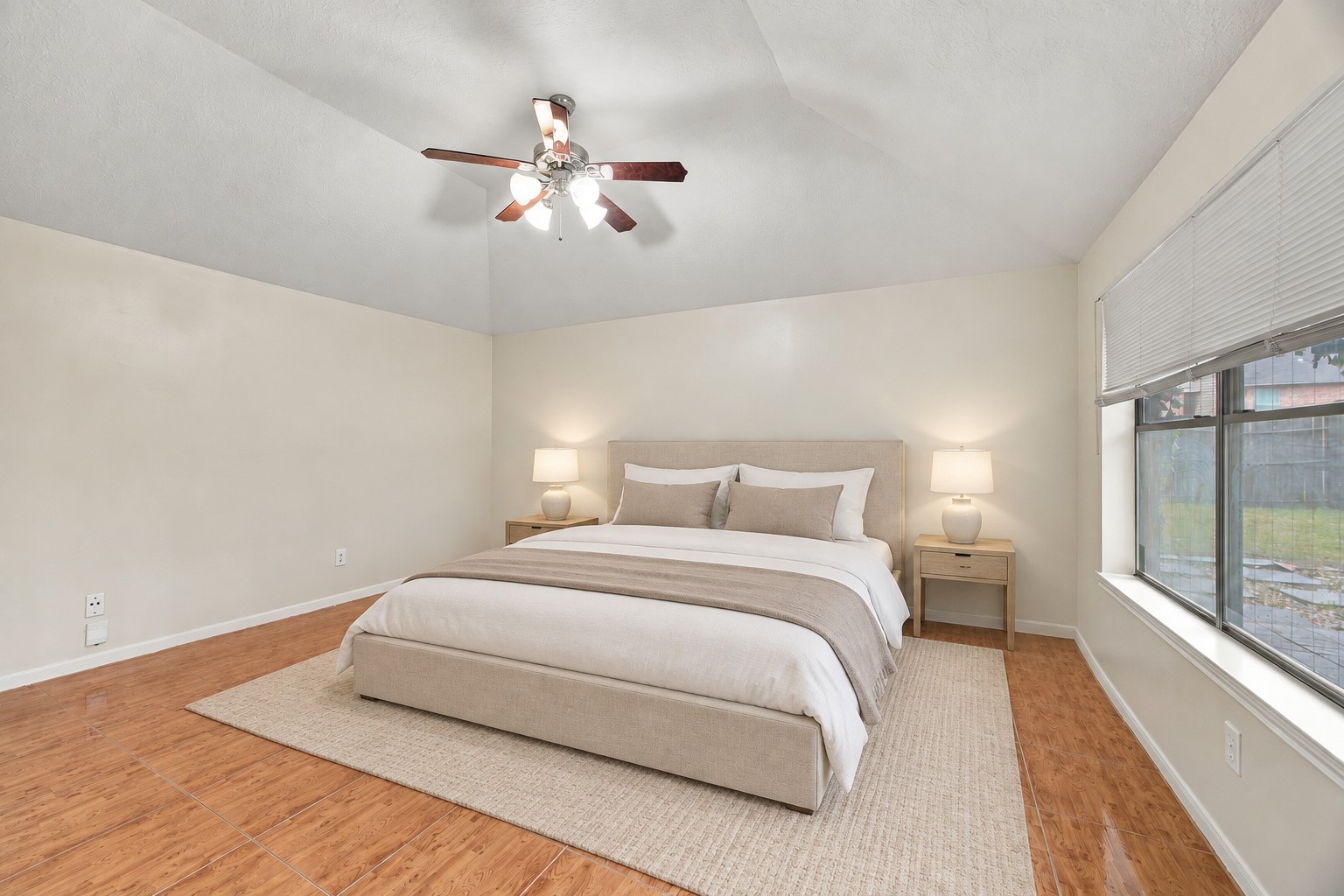 The spacious primary bedroom features a raised ceiling, a ceiling fan, and room for a variety of furniture arrangements. Virtually staged