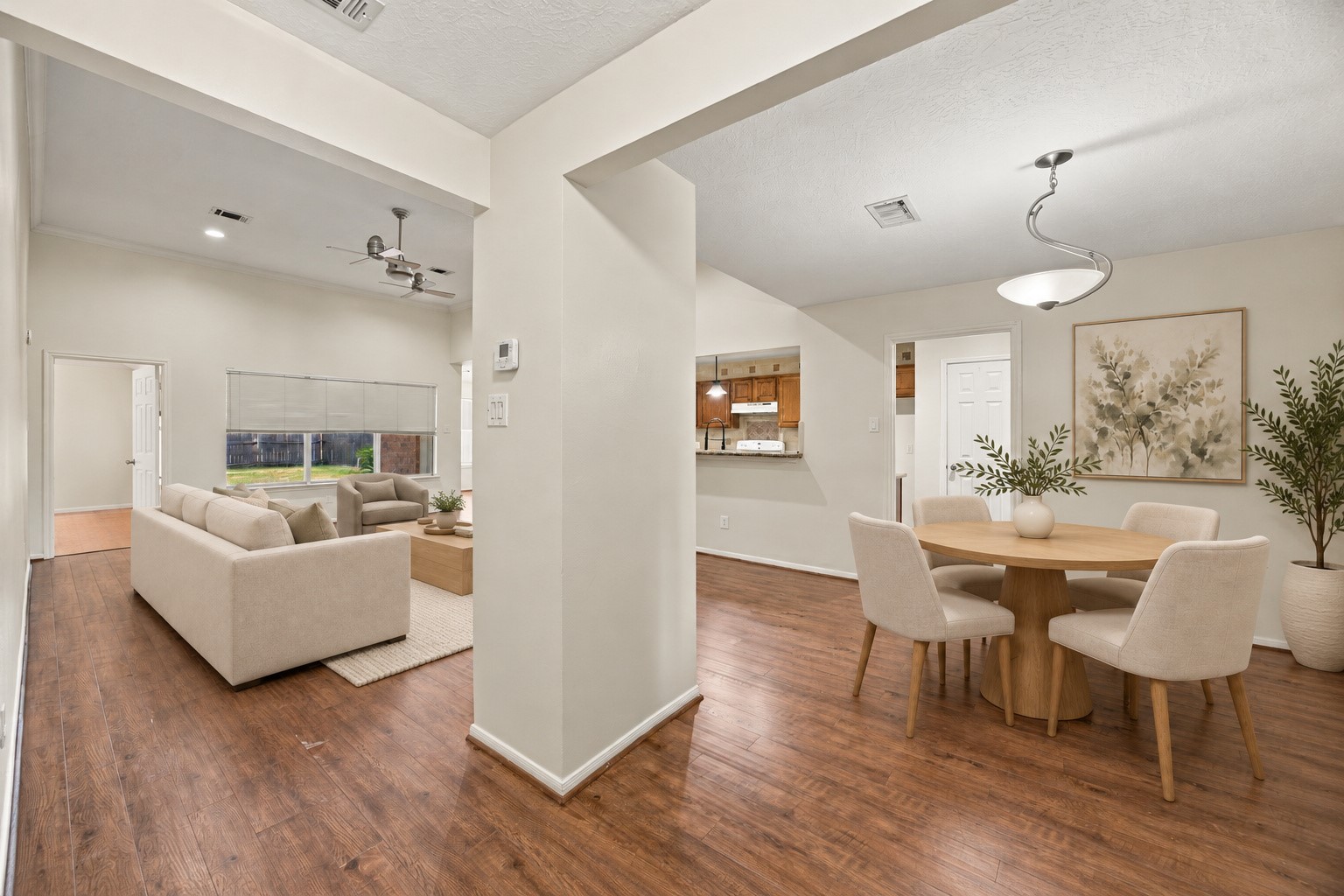 Wide openings connect the dining and living areas, while a kitchen pass-through keeps the spaces connected. Virtually staged
