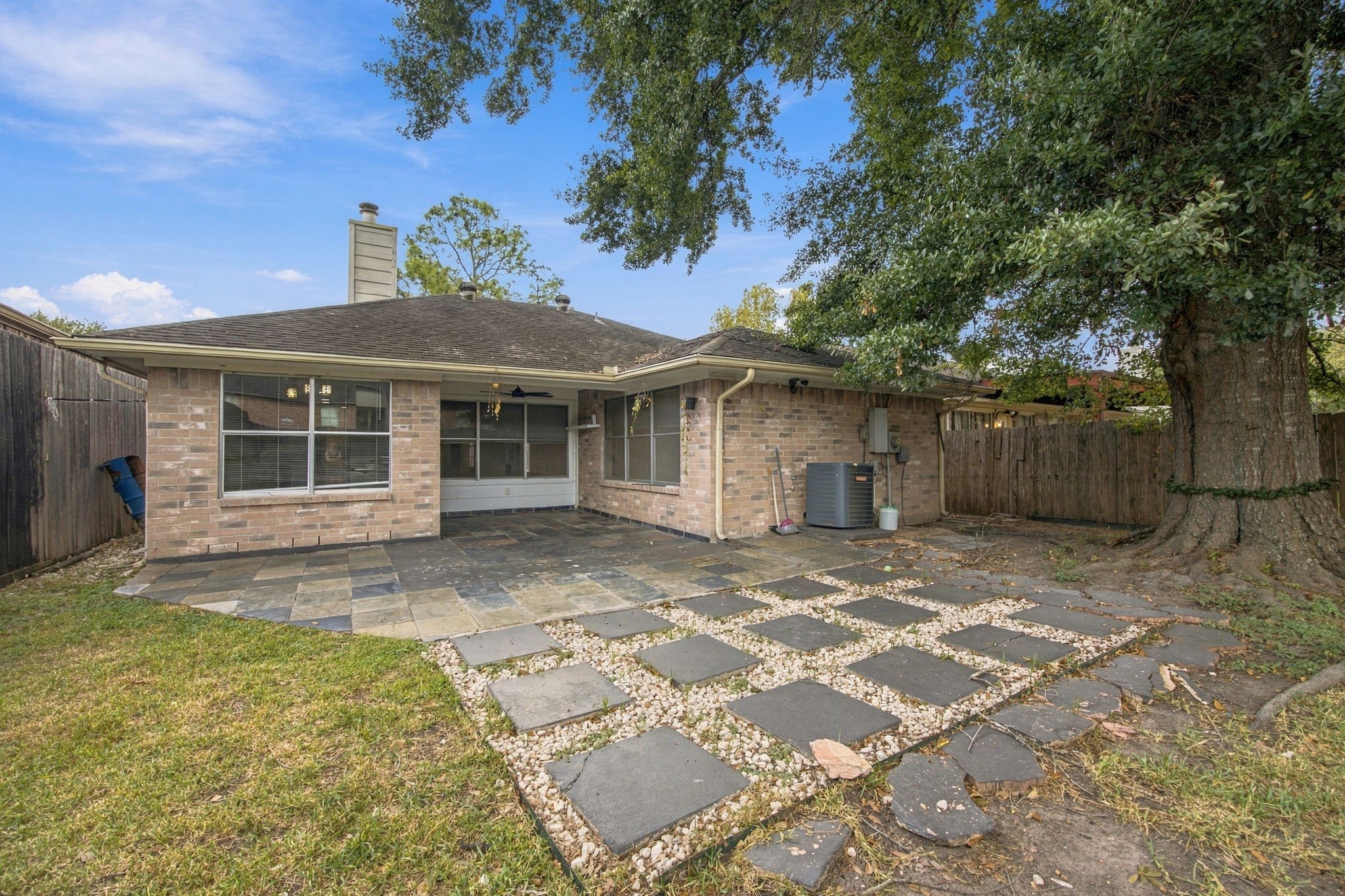 The brick exterior overlooks an extended patio with a decorative paver-and-gravel design.