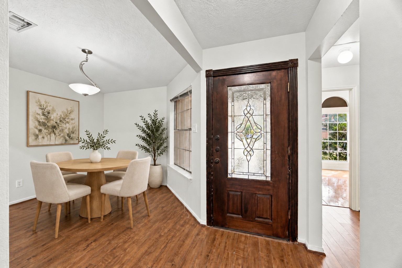 The entry opens to a formal dining room with wood-look flooring flowing throughout. Virtually staged.