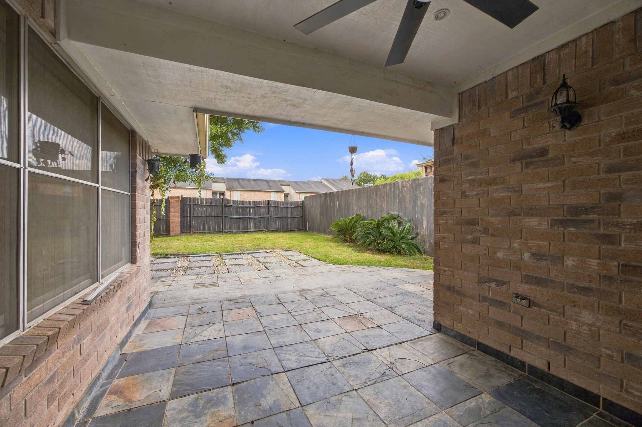 Enjoy a shaded outdoor seating area with tile flooring, a ceiling fan, and views of the backyard.